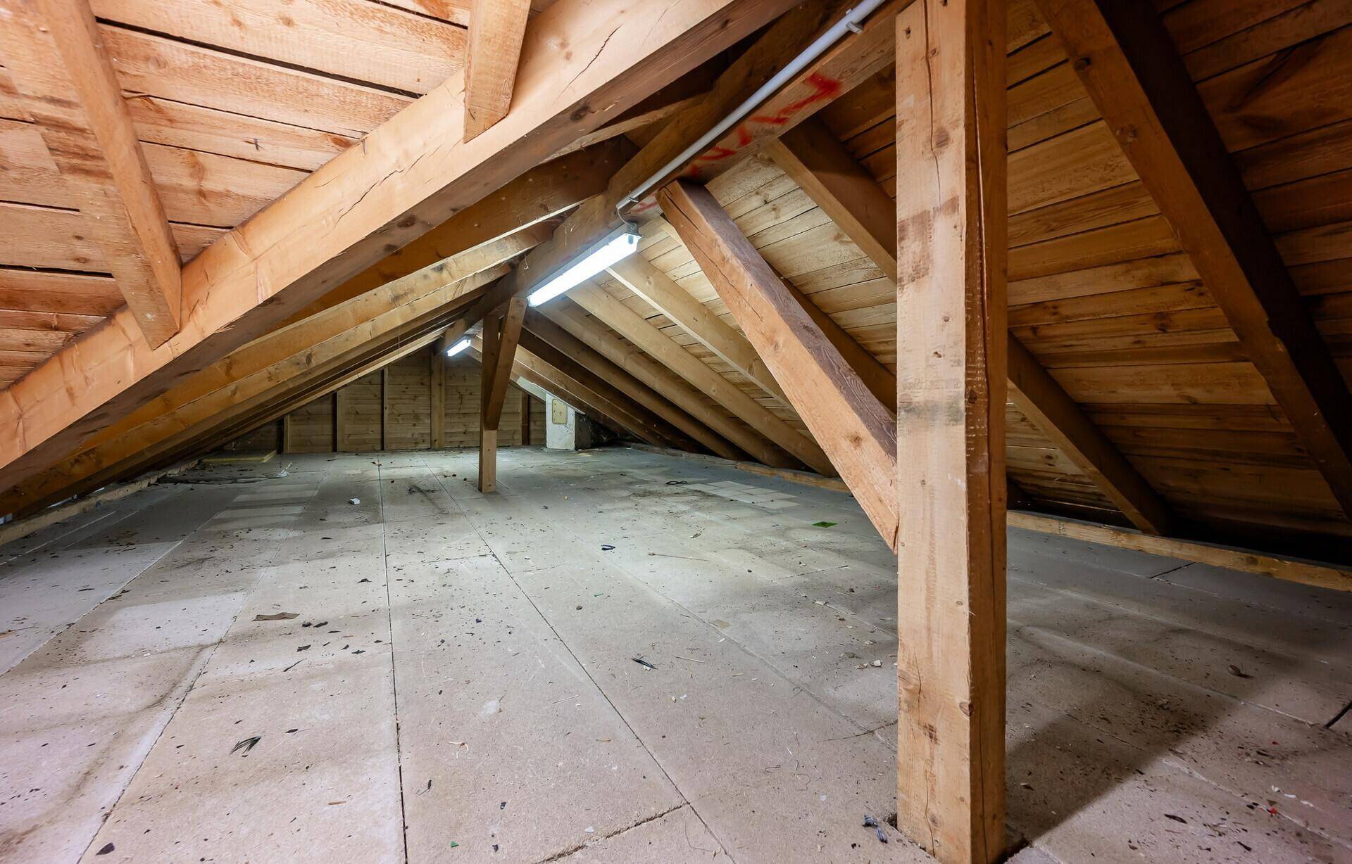 Unausgebauter Dachboden mit sichtbaren Holzbalken und Dachschrägen.