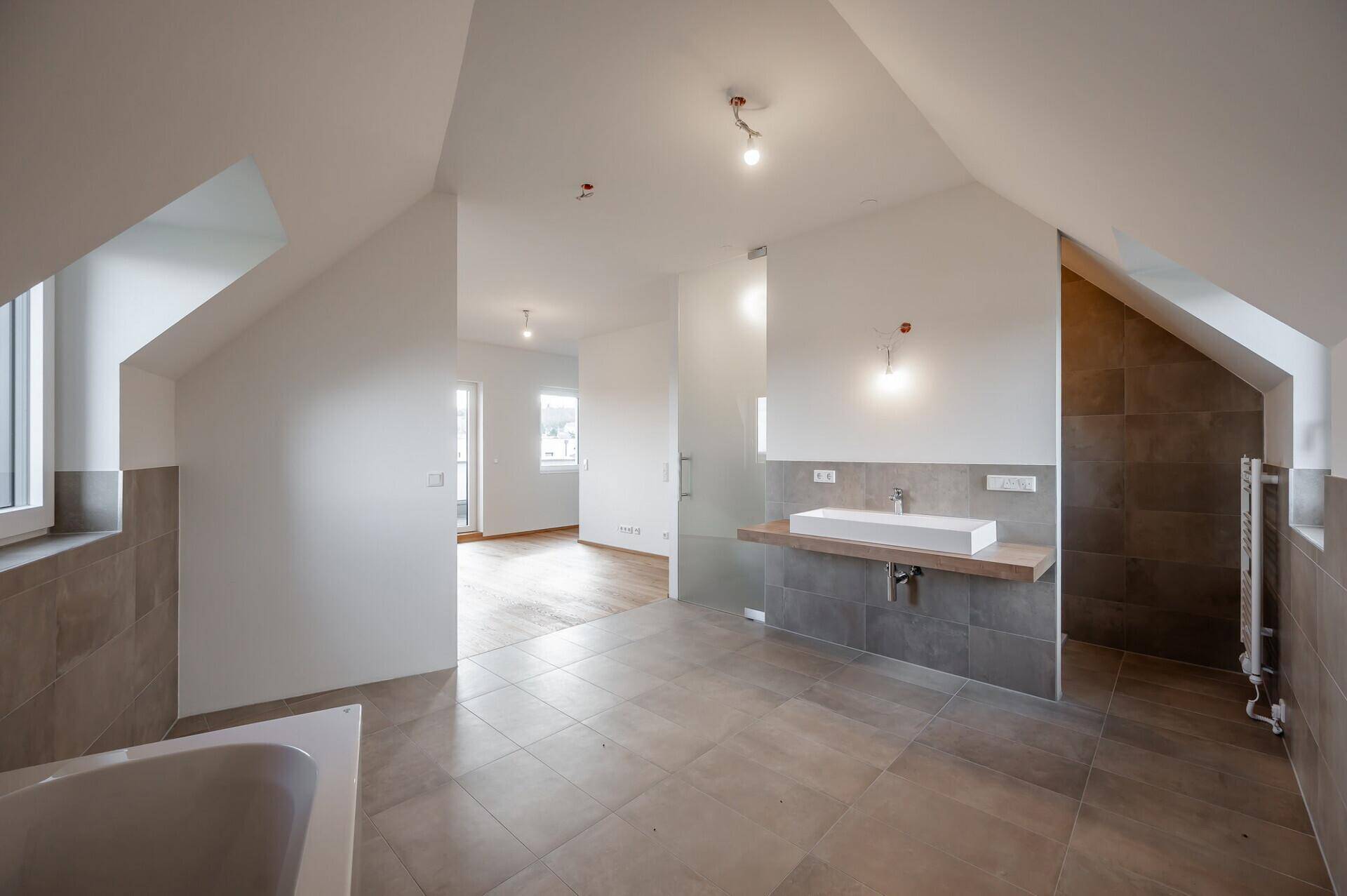Großes Badezimmer im Dachgeschoss mit Badewanne, Dusche und Einzelwaschbecken.