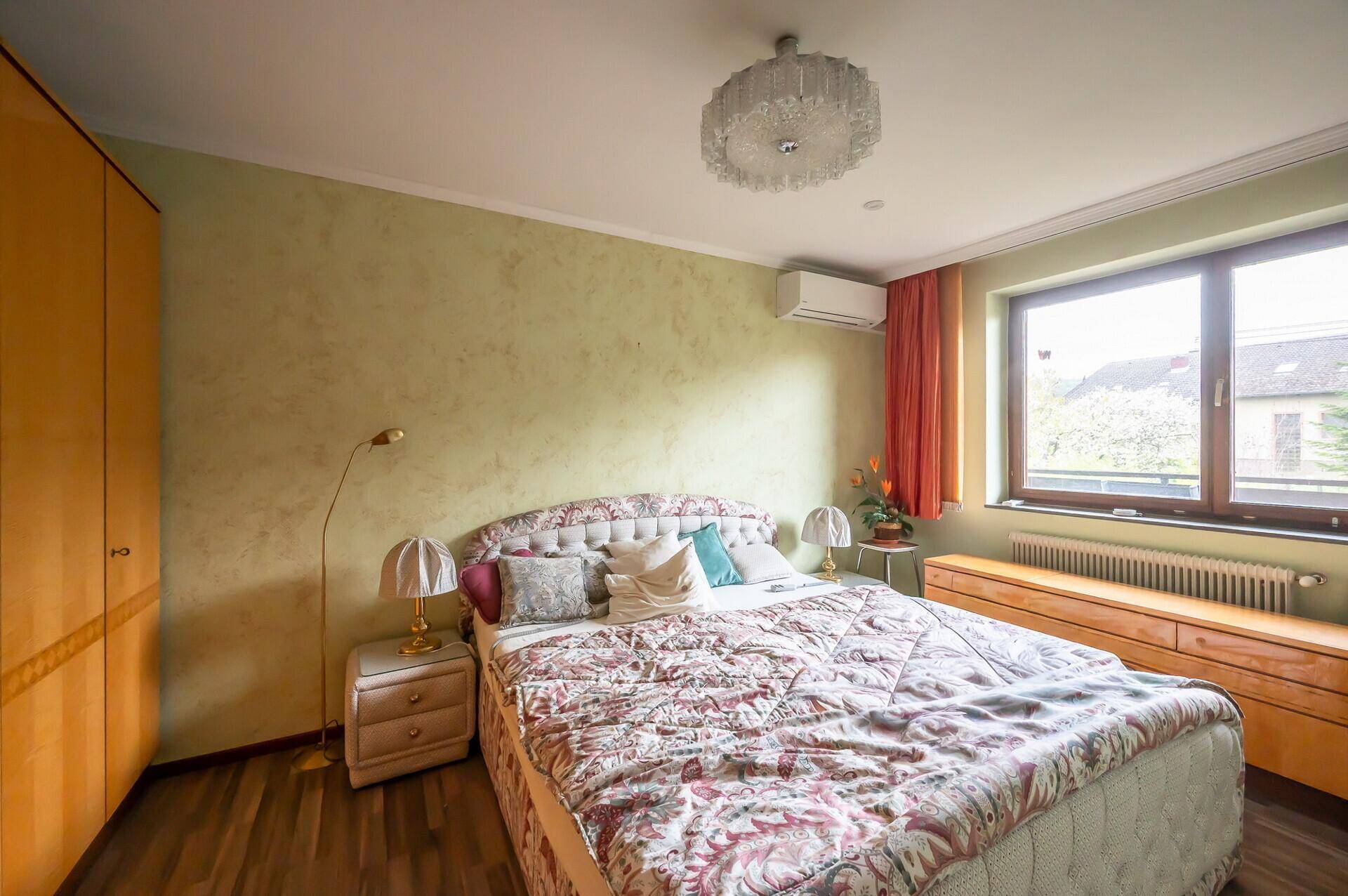 Gemütliches Schlafzimmer mit Doppelbett, Kleiderschrank und Klimaanlage.