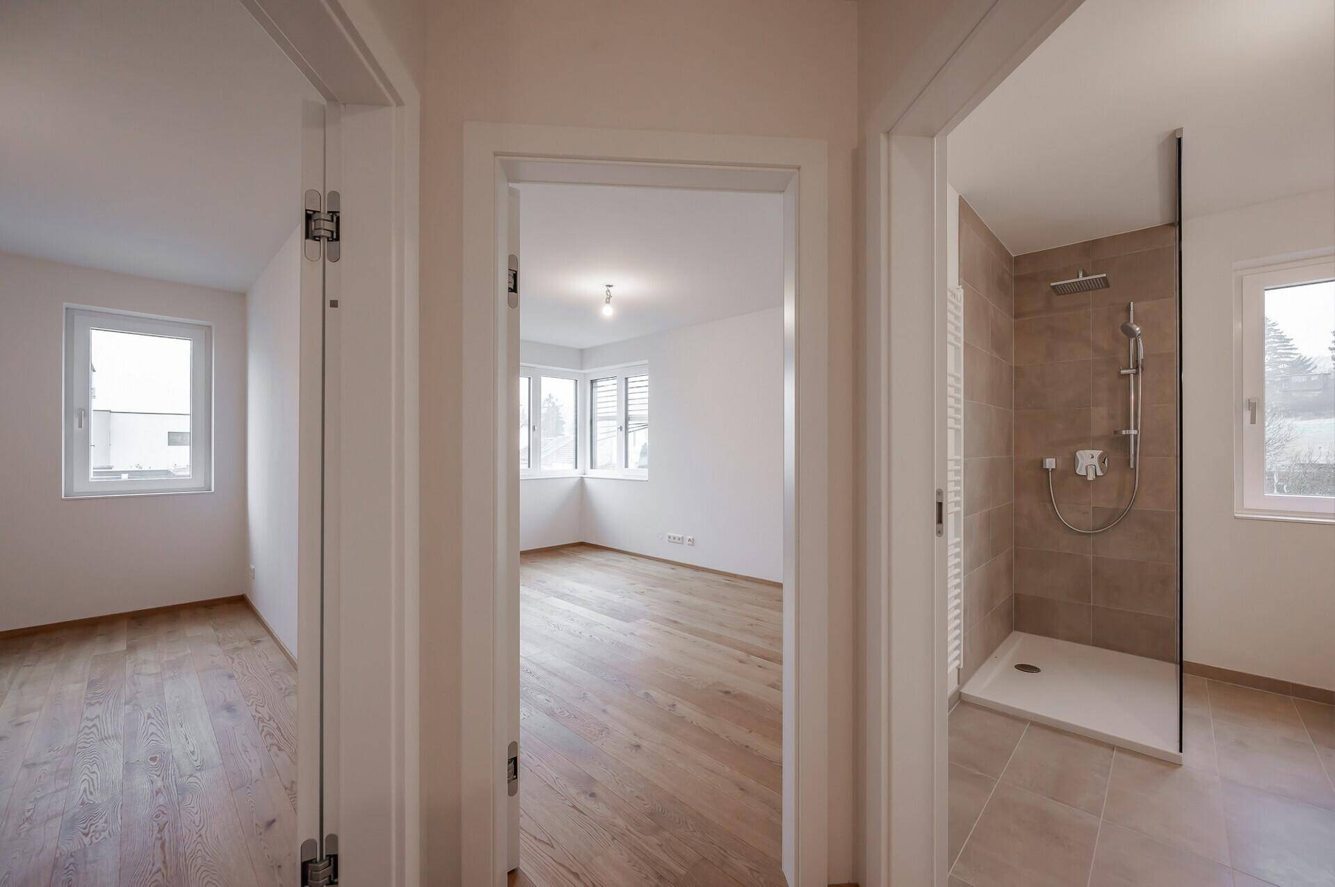 Flur mit Zugang zu einem Schlafzimmer und einem modernen Badezimmer mit Dusche.