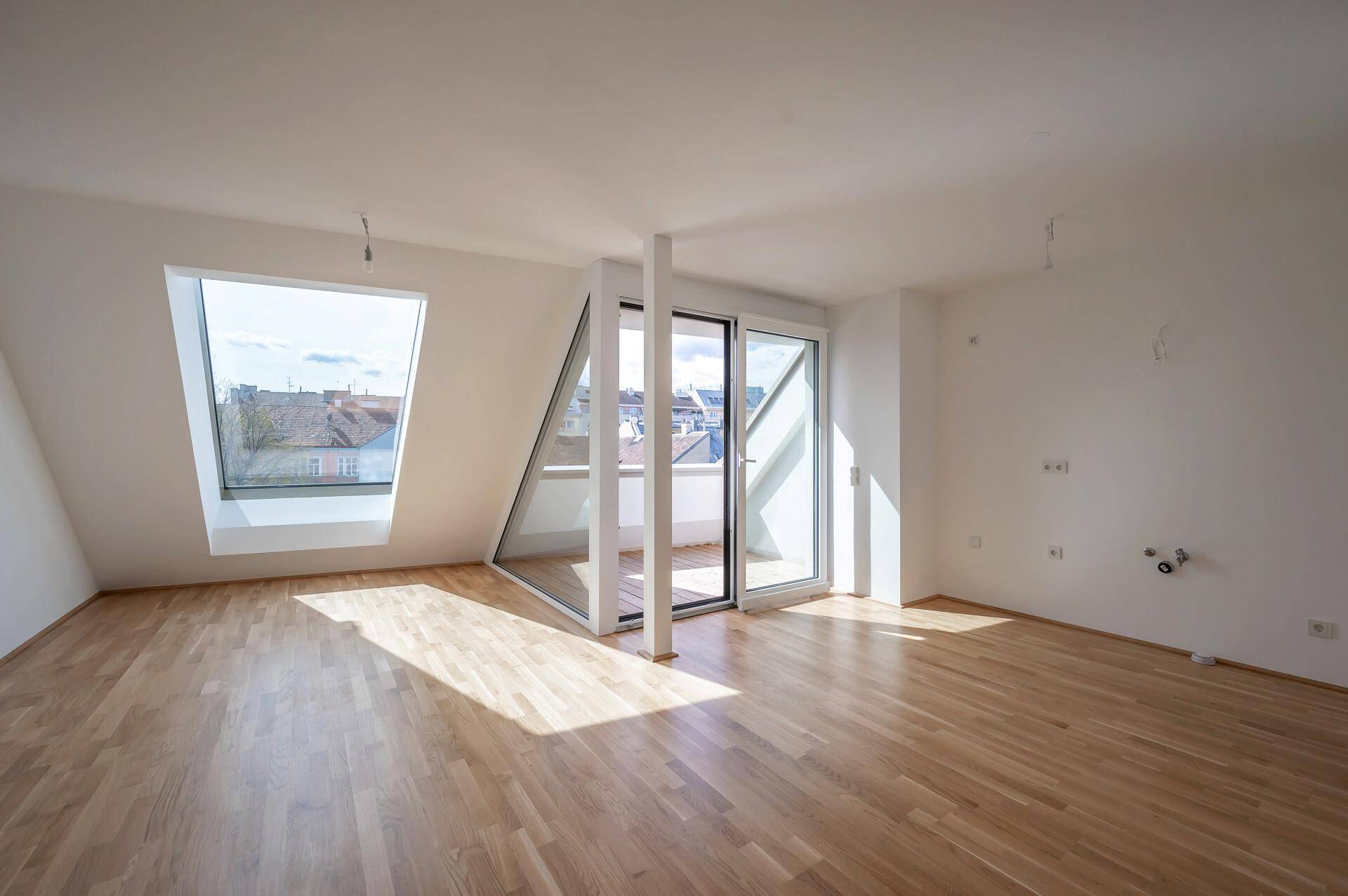Heller Wohnraum mit Holzboden, Dachschrägen und einem großen Dachfenster für viel Licht.