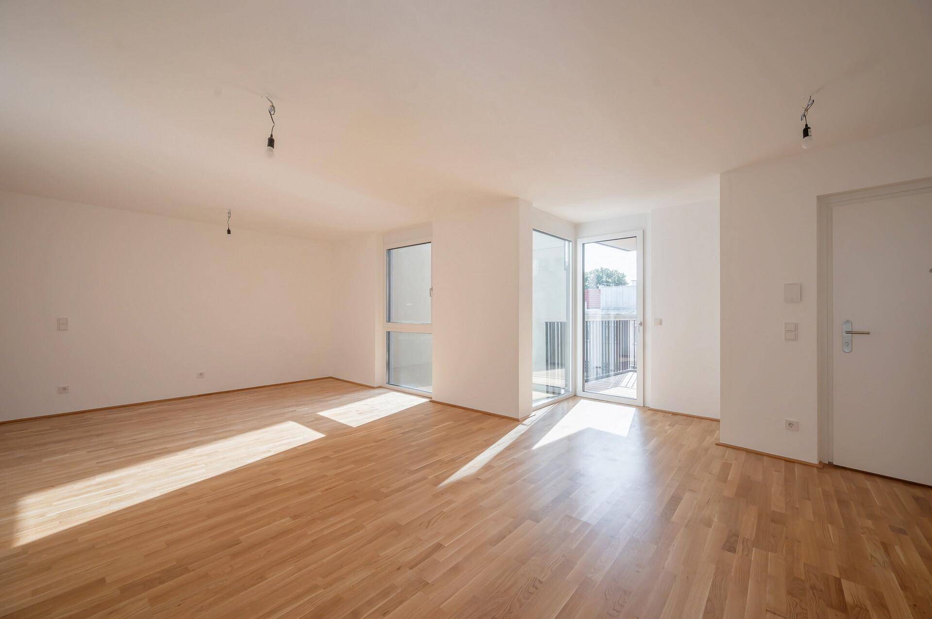 Heller, leerer Wohnraum mit Parkettboden und Zugang zu einem Balkon, ideal für individuelle Gestaltung.