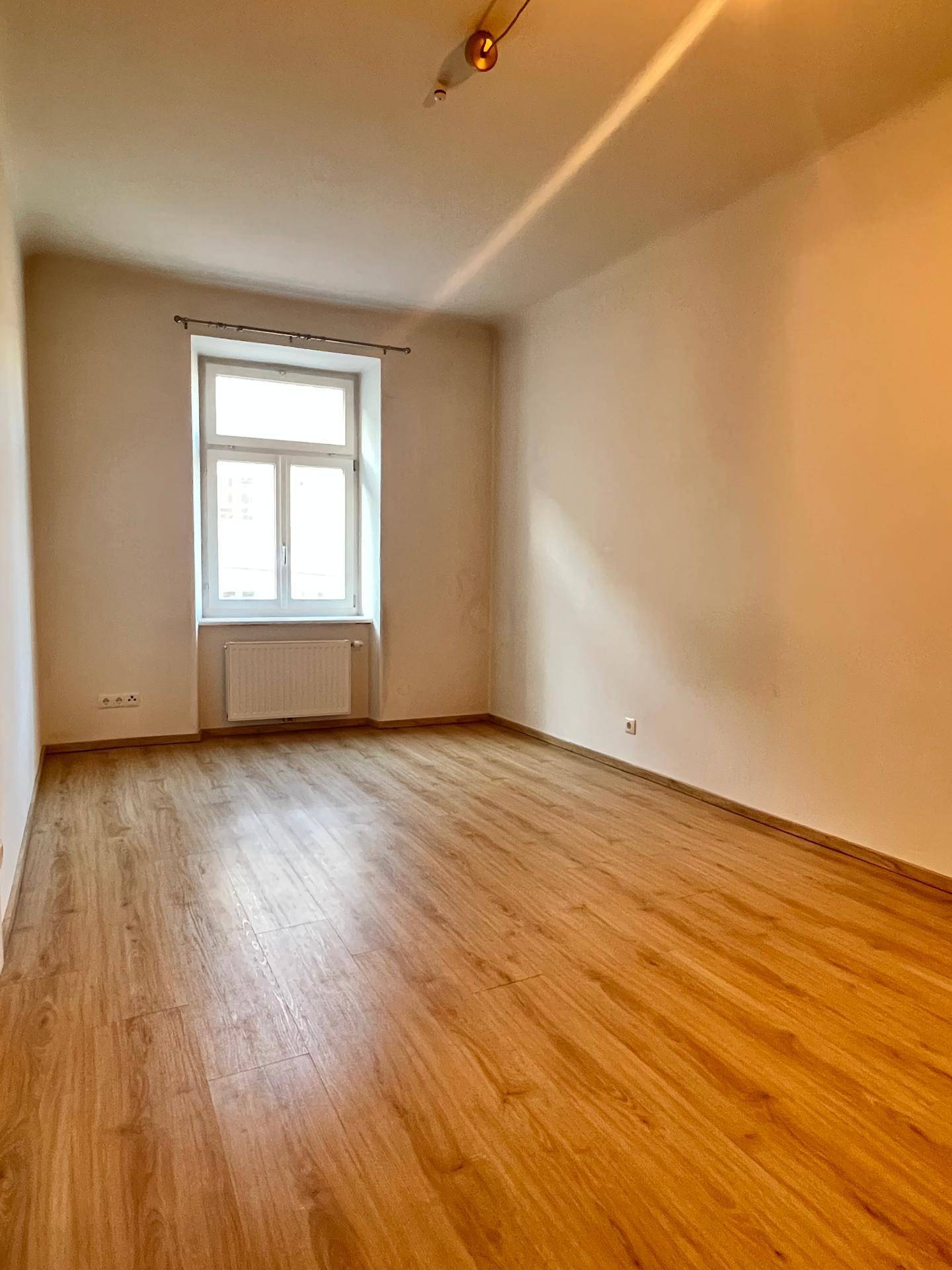 Ruhiges Zimmer mit Laminatboden und einem Fenster, das für ausreichend natürliche Belichtung sorgt.