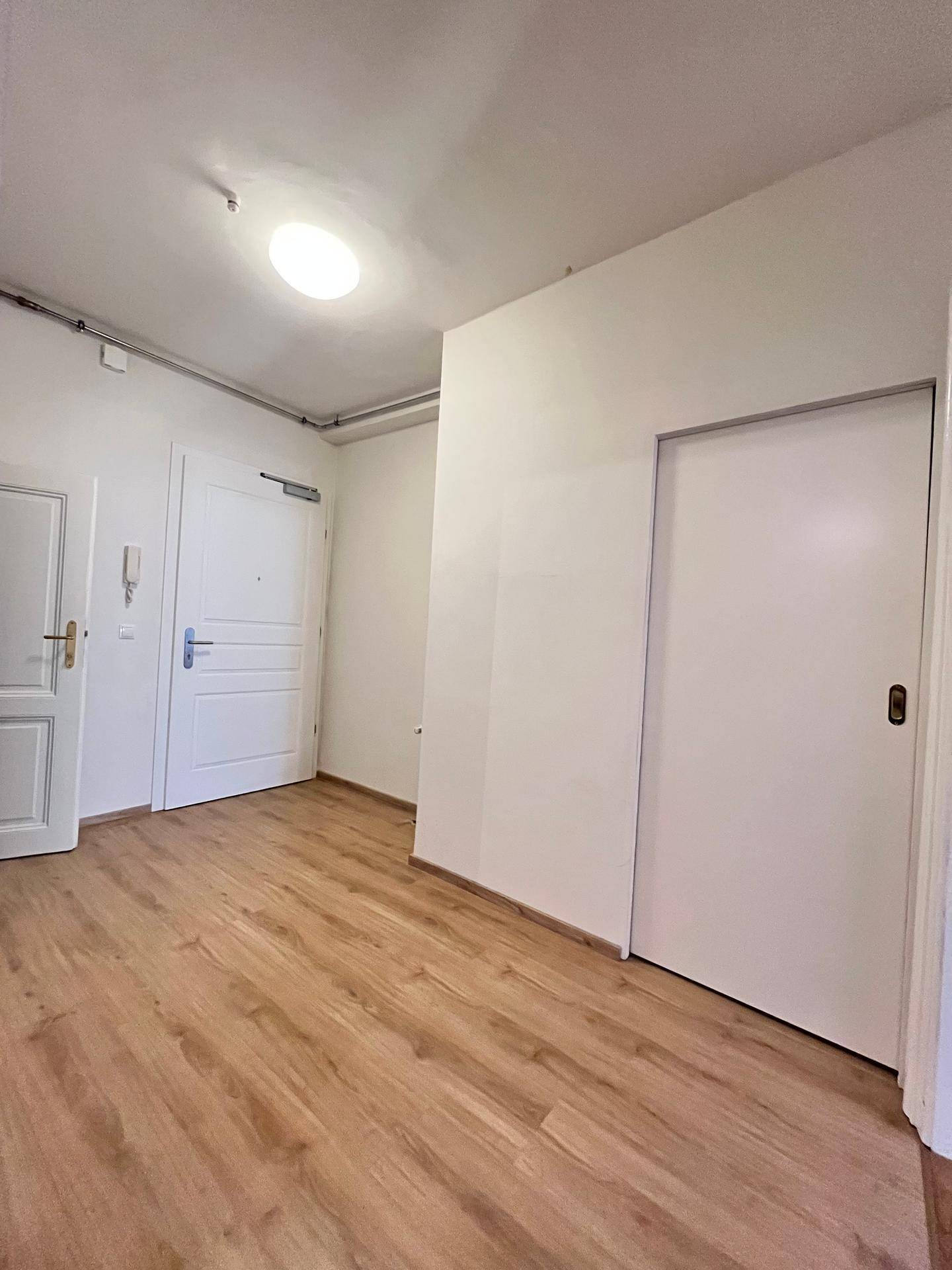 Heller Eingangsbereich mit Laminatboden und mehreren Türen, die zu den Wohnräumen führen.