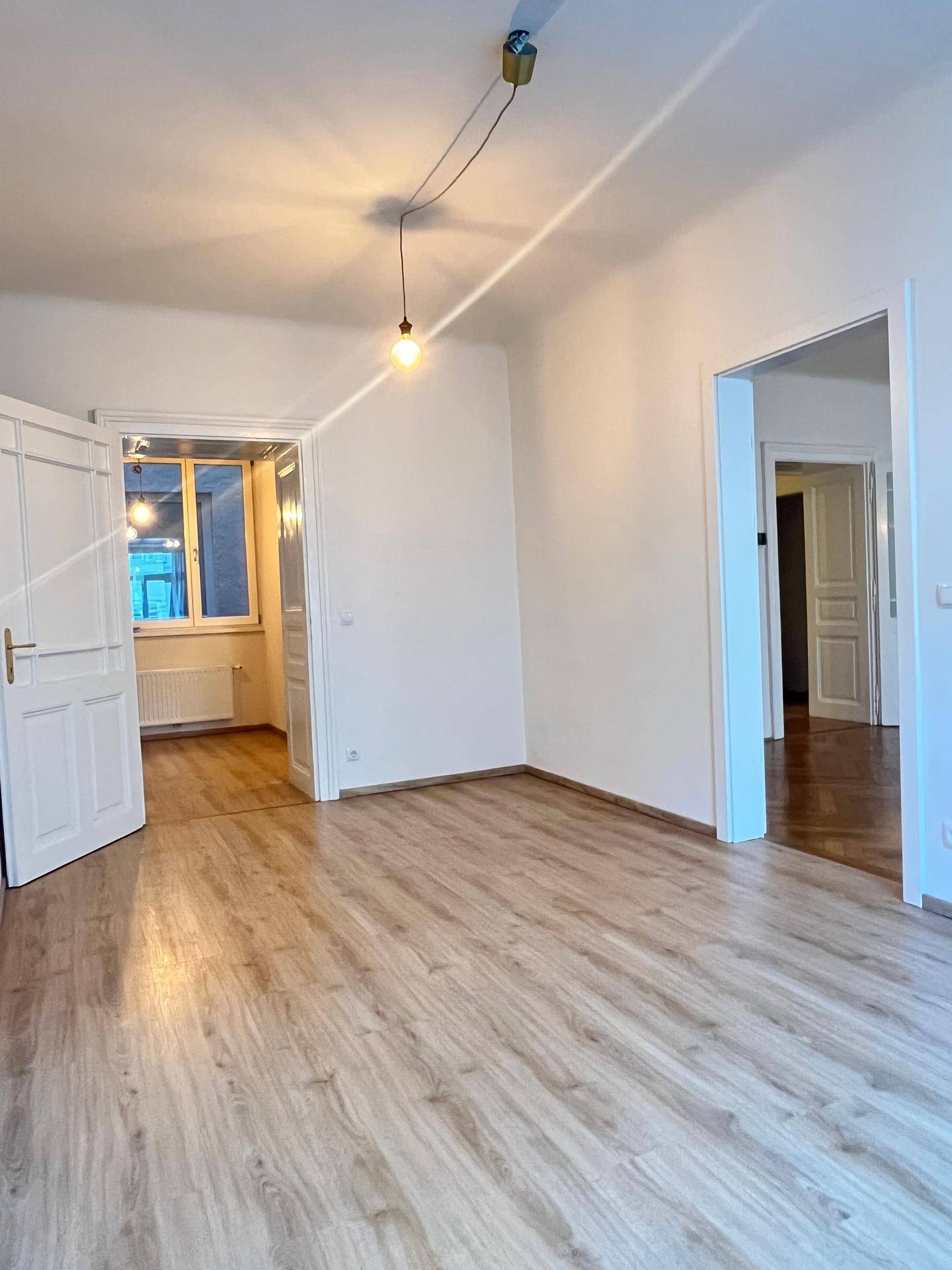 Übergangsbereich mit Laminatboden und Blick in angrenzende Zimmer mit unterschiedlichen Bodenbelägen.