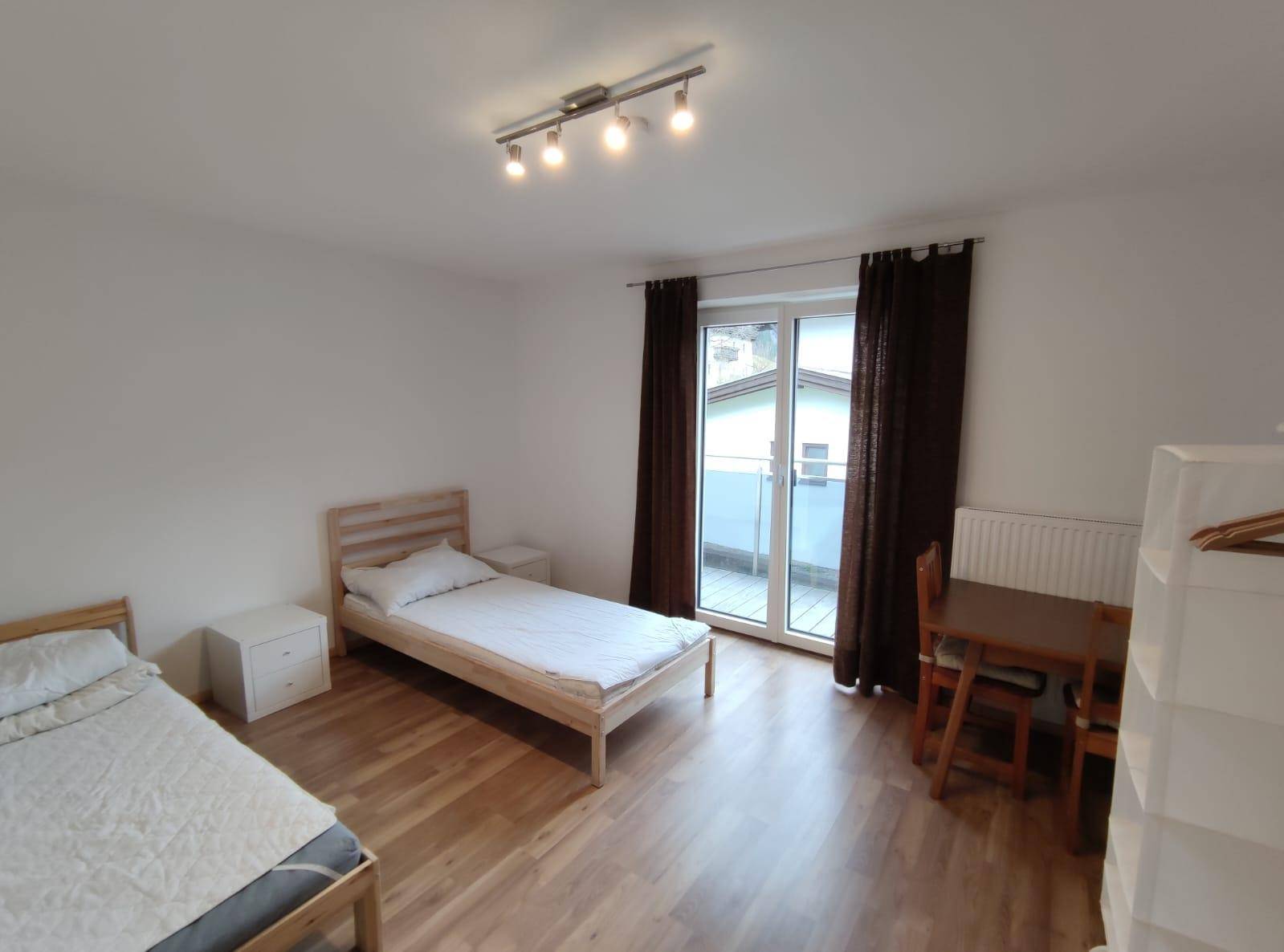 Helles Schlafzimmer mit zwei Einzelbetten, kleinem Tisch und direktem Zugang zum Balkon.