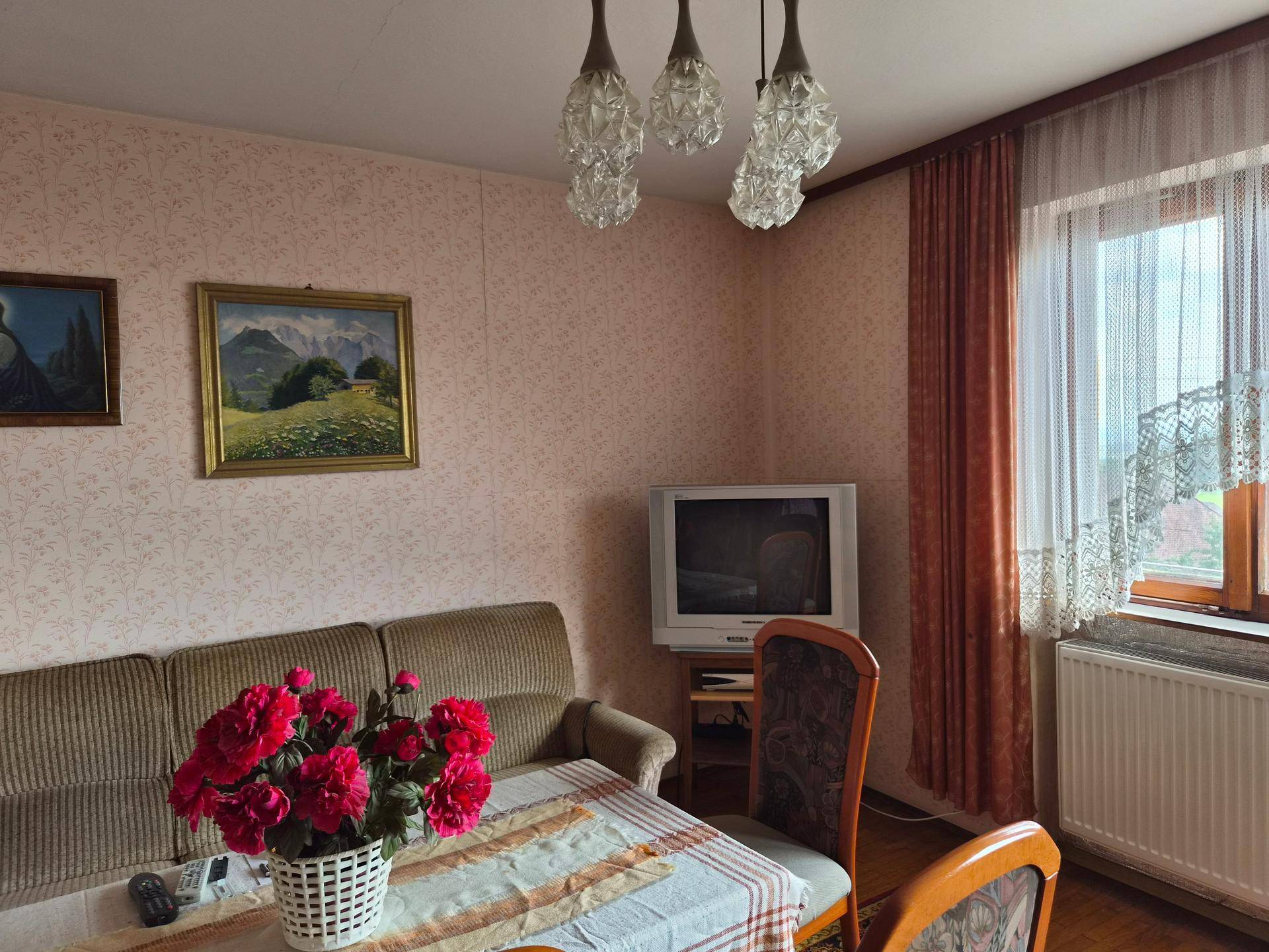 Gemütlicher Wohn- und Essbereich mit floraler Tapete, Sofa und Esstisch in traditionellem Stil.