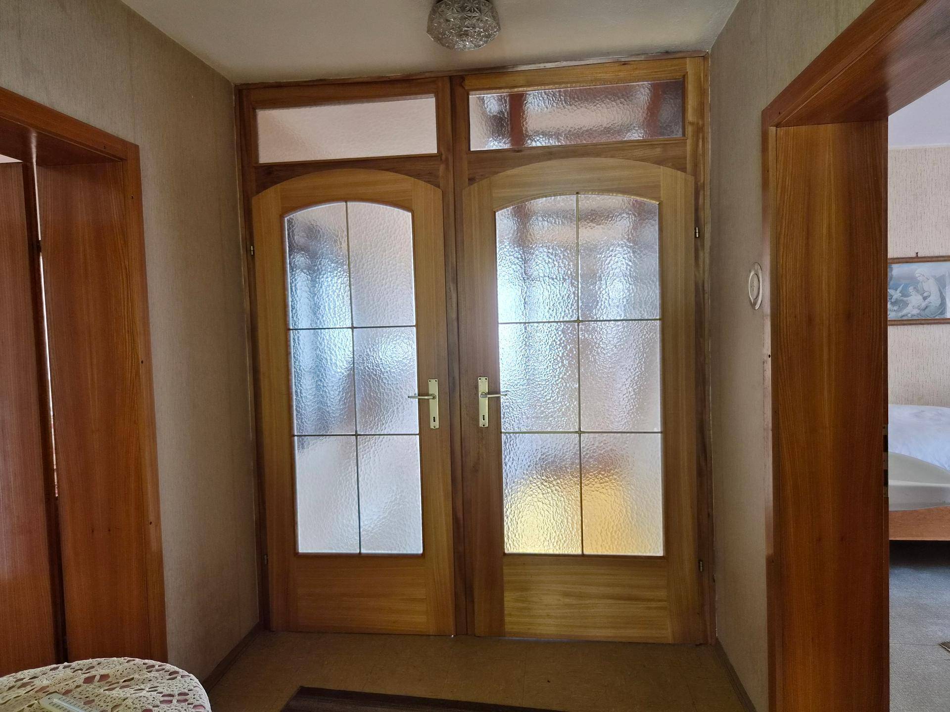 Flur mit zwei Holztüren und satinierten Glaseinsätzen, die zu weiteren Räumen führen.