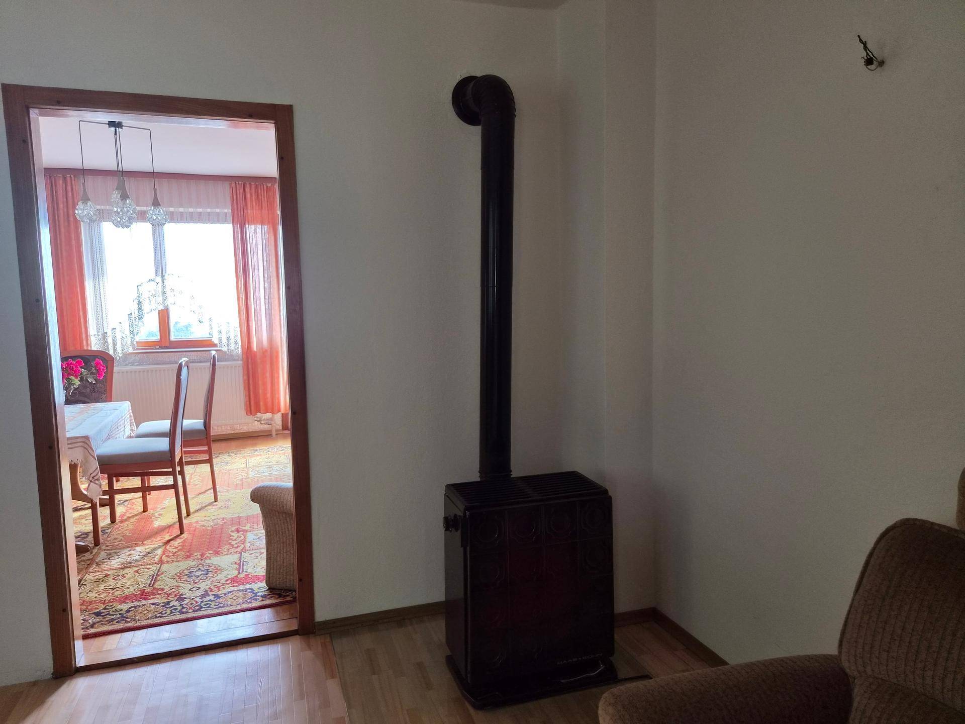 Wohnbereich mit einem Holzofen und Blick durch eine offene Tür in einen weiteren Raum.