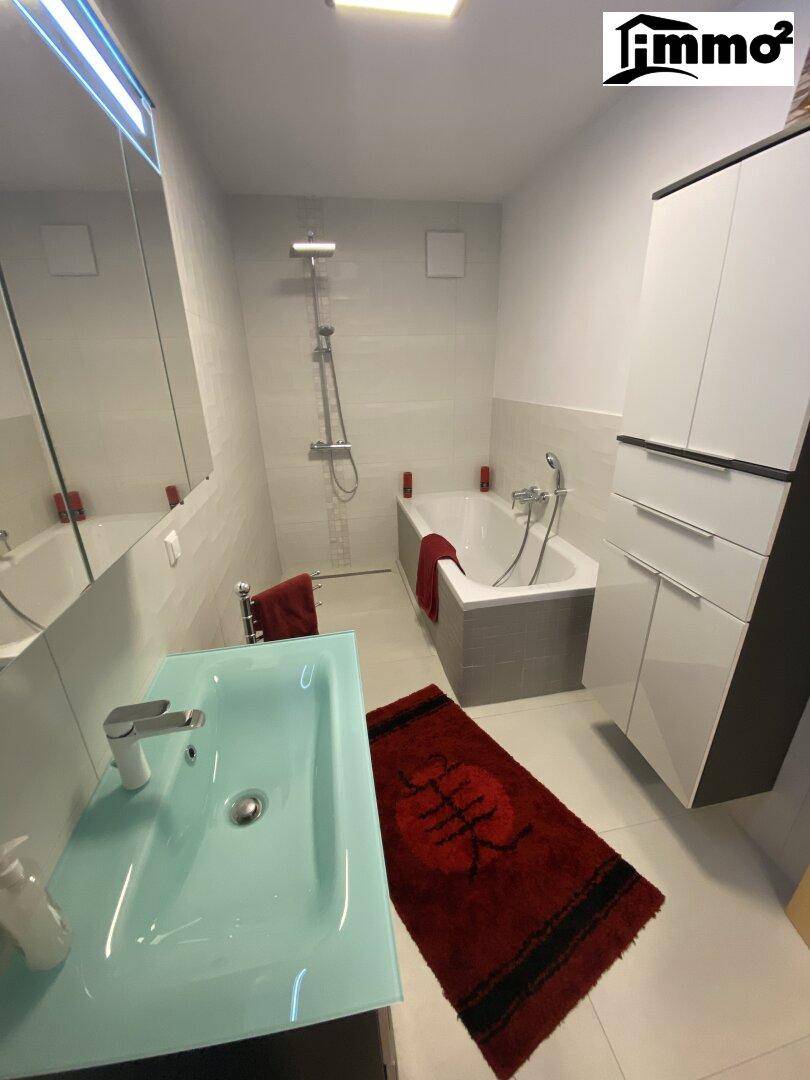 Modernes Badezimmer mit Badewanne, Dusche, Einzelwaschbecken und Spiegelschrank.