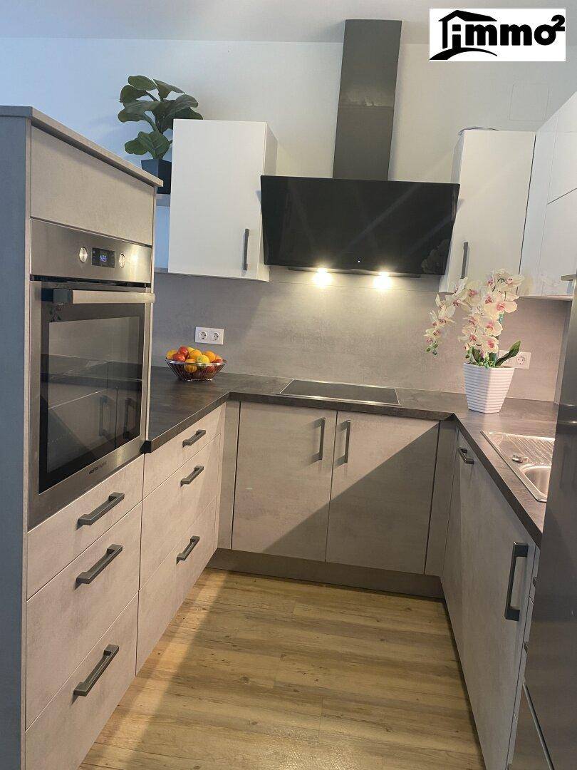 Moderne Einbauküche in Grau und Weiß mit integriertem Backofen und Dunstabzugshaube.