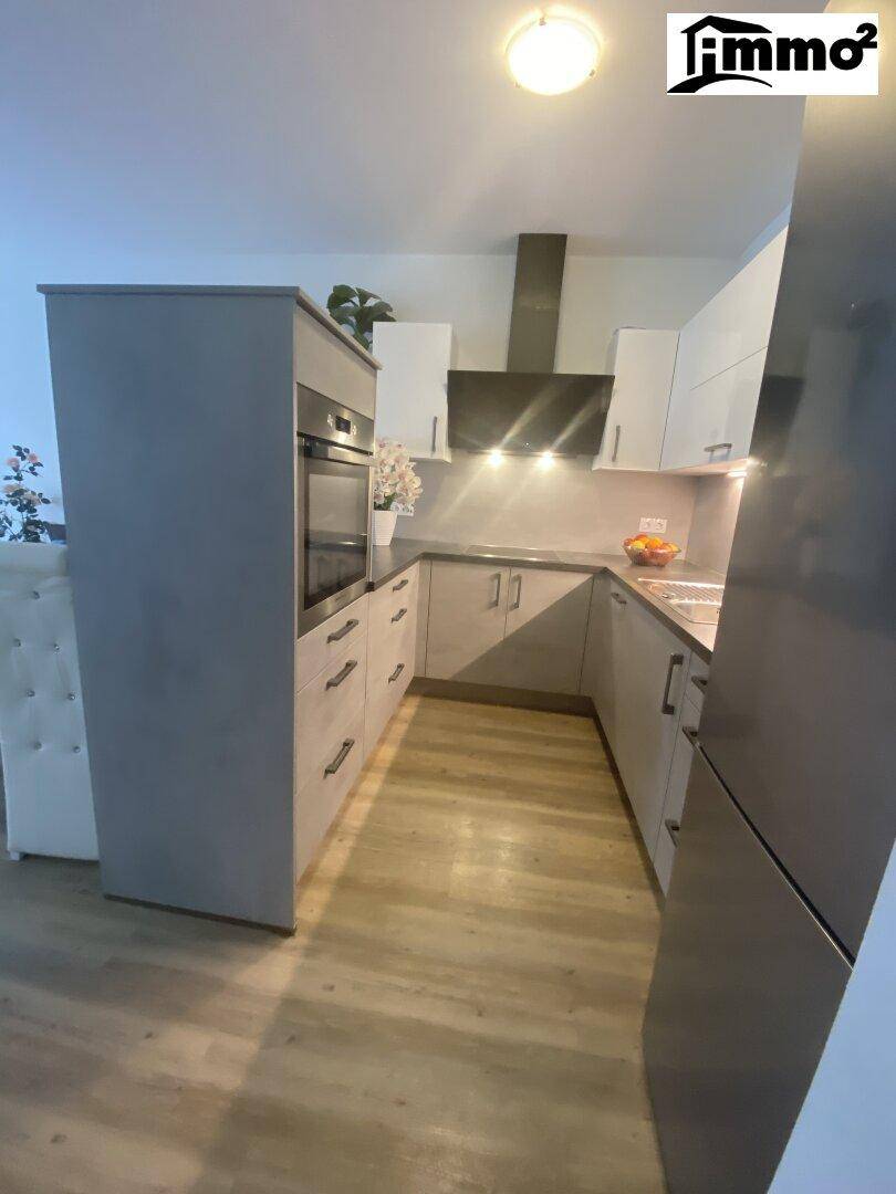 Moderne Einbauküche in Grau und Weiß mit integriertem Backofen und Dunstabzugshaube.