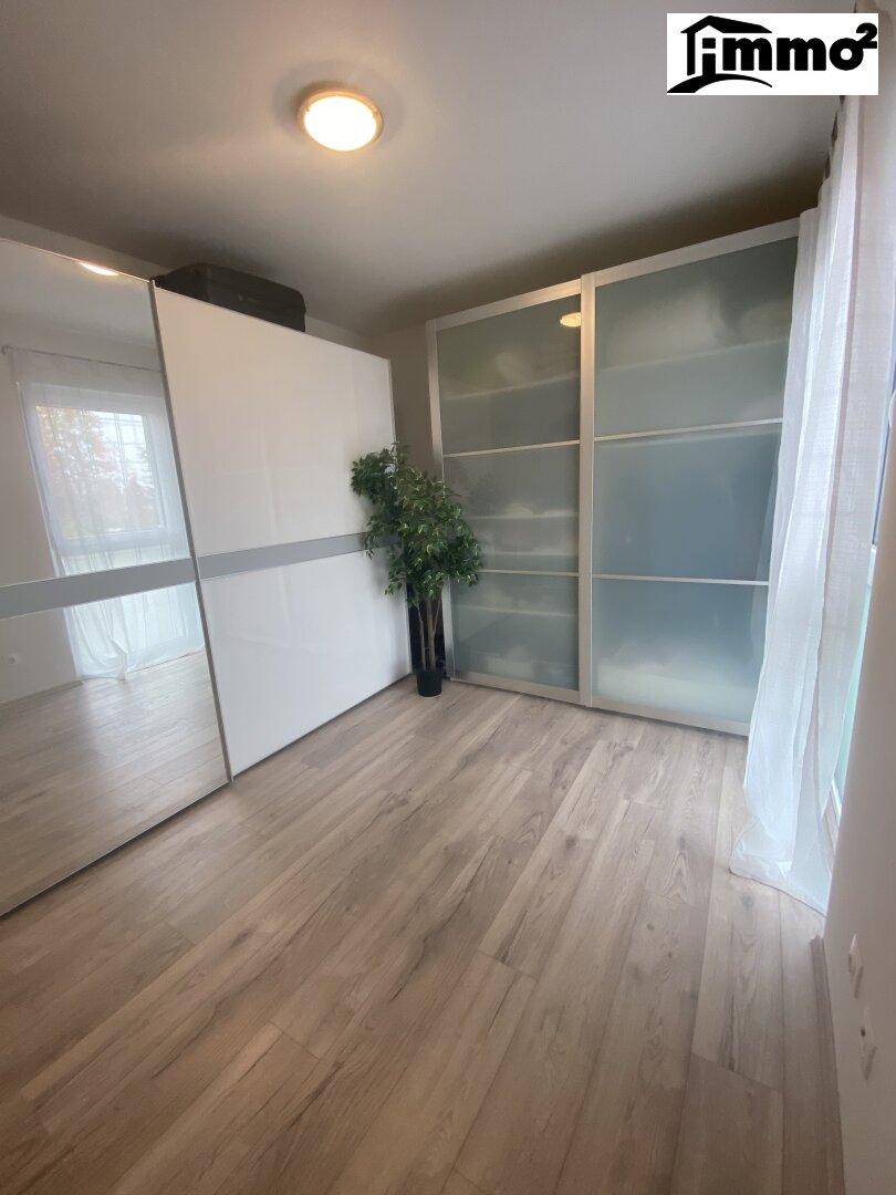 Helles Schlafzimmer mit großem Schiebetürenschrank und modernem Laminatboden.