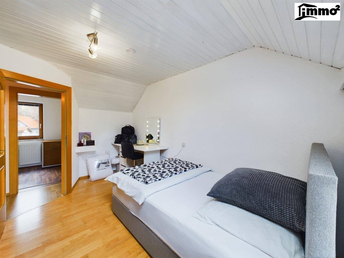 Dachgeschoss-Schlafzimmer mit Holzboden, Einzelbett und Schminktisch.