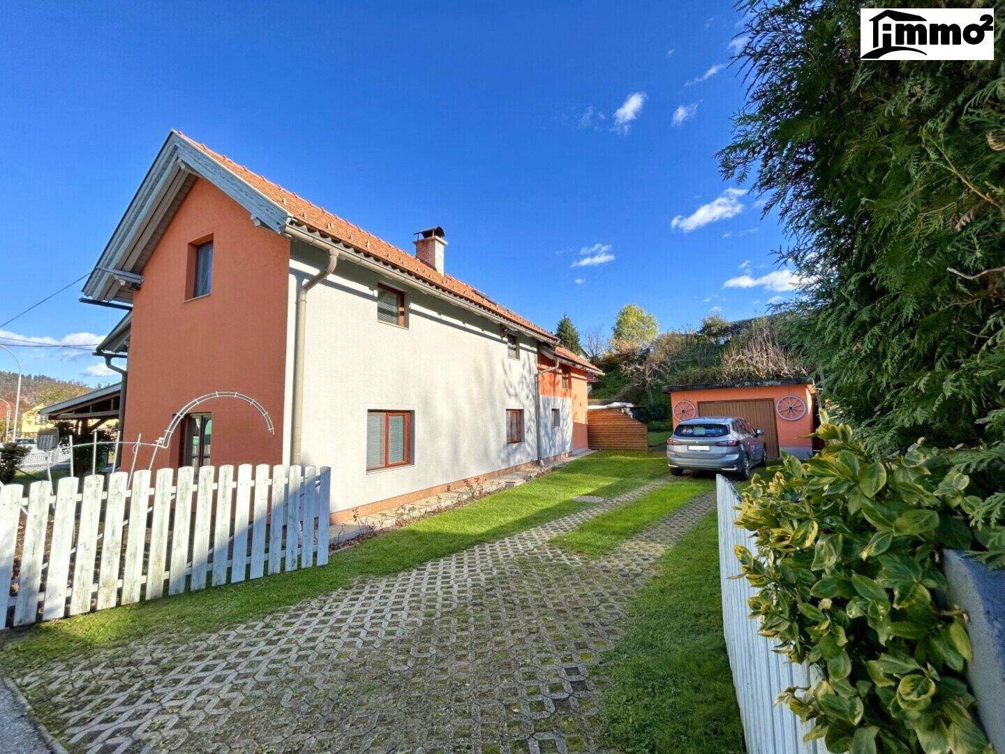 Seitenansicht des Hauses mit gepflasterter Auffahrt und angrenzendem Gartenbereich.