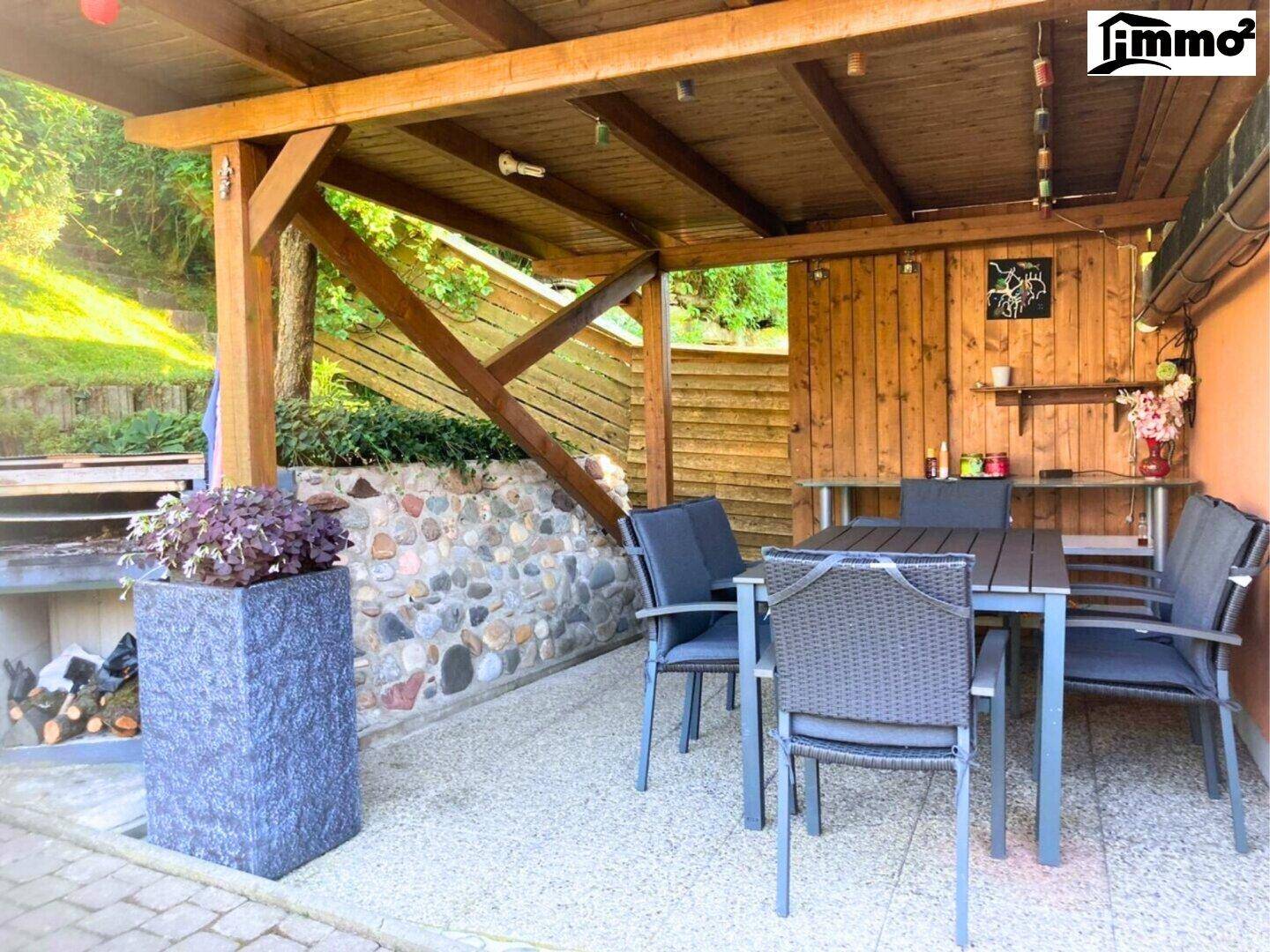 Überdachte Terrasse mit Esstisch und Stühlen, ideal für Mahlzeiten im Freien.