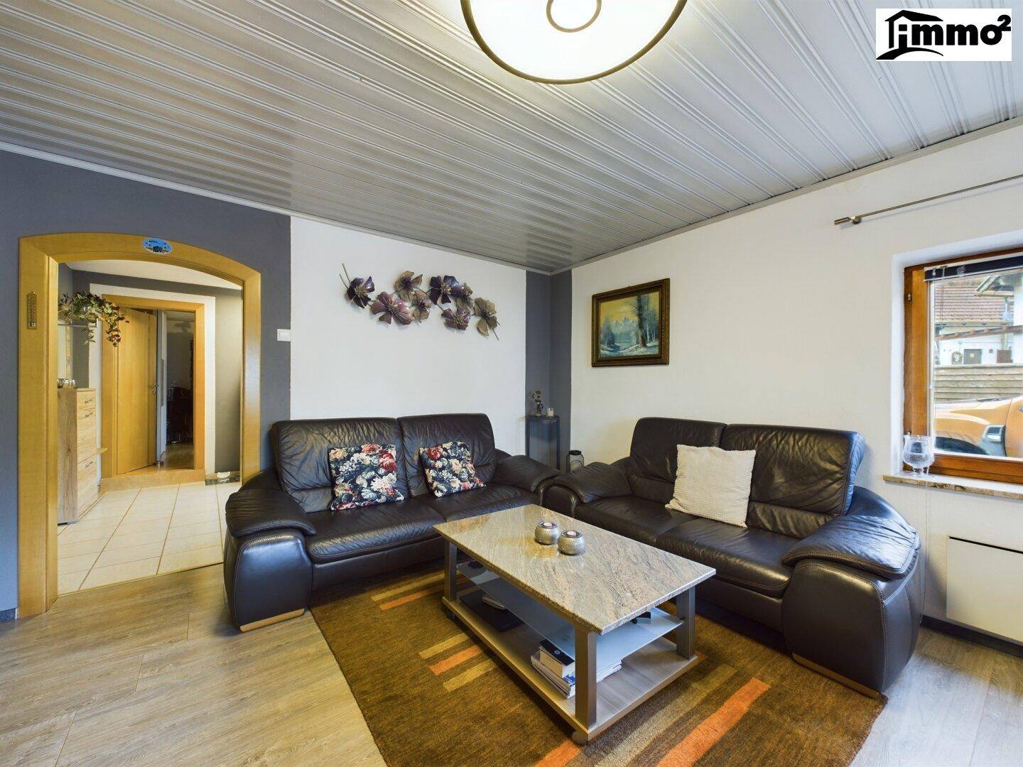 Gemütliches Wohnzimmer mit Ledersofas, Couchtisch und Blick nach draußen.