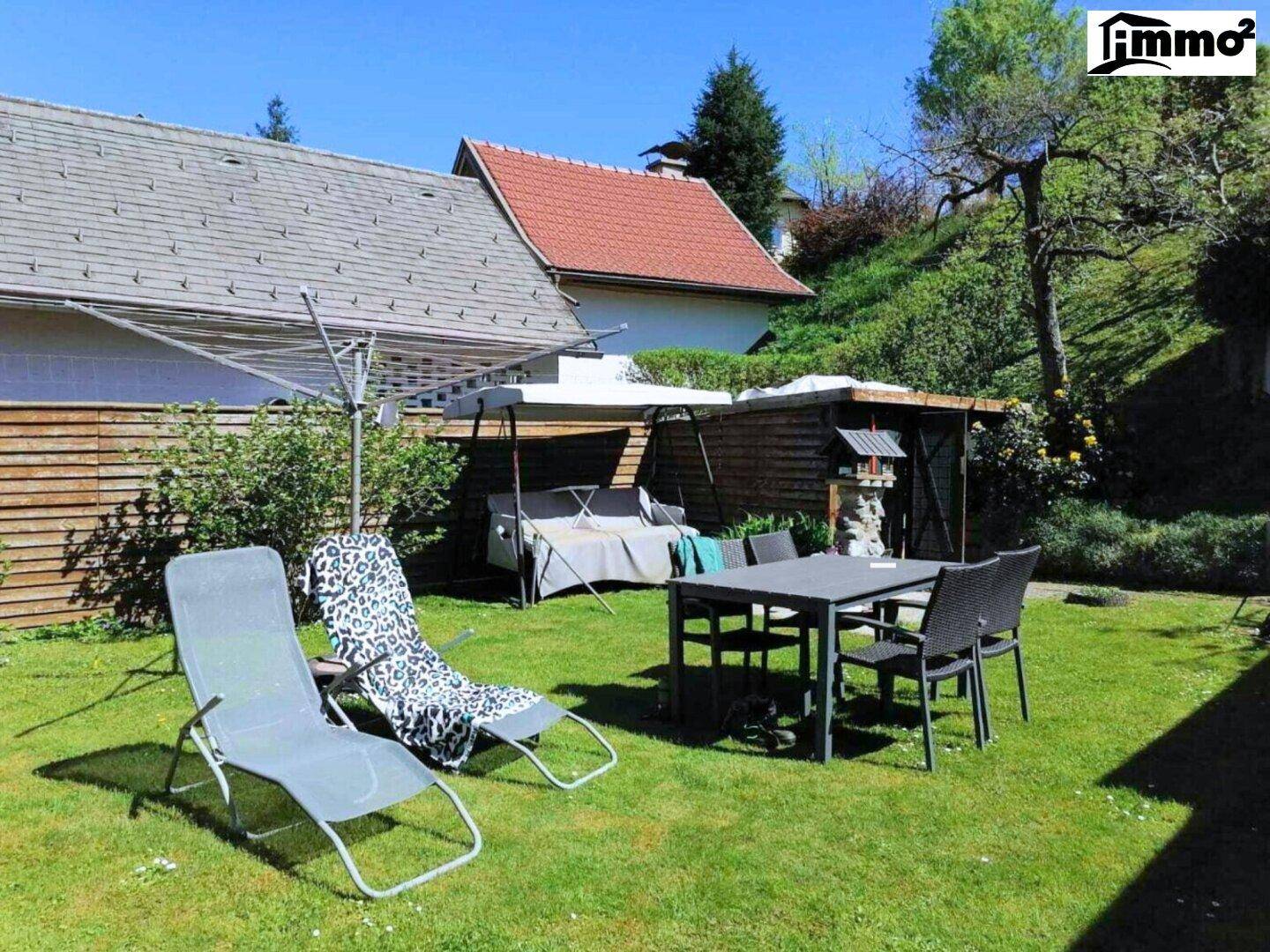 Sonnige Rasenfläche im Garten mit Liegestühlen und Sitzgelegenheiten.