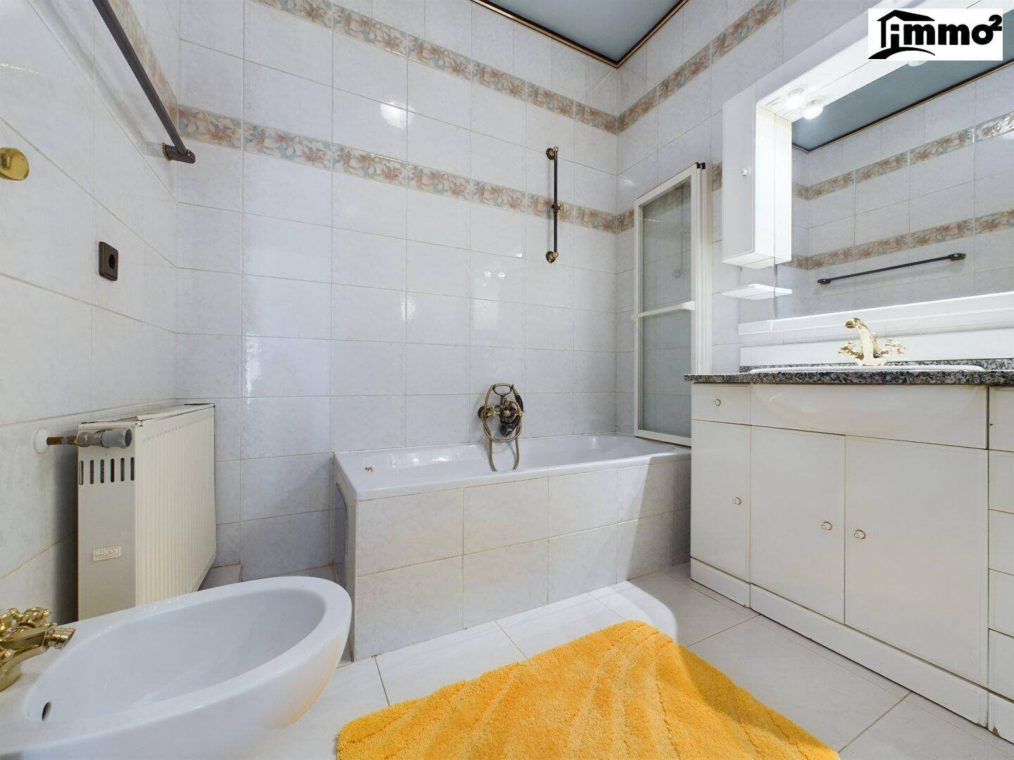 Helles Badezimmer mit Badewanne, Bidet und Fliesen in klassischem Design.