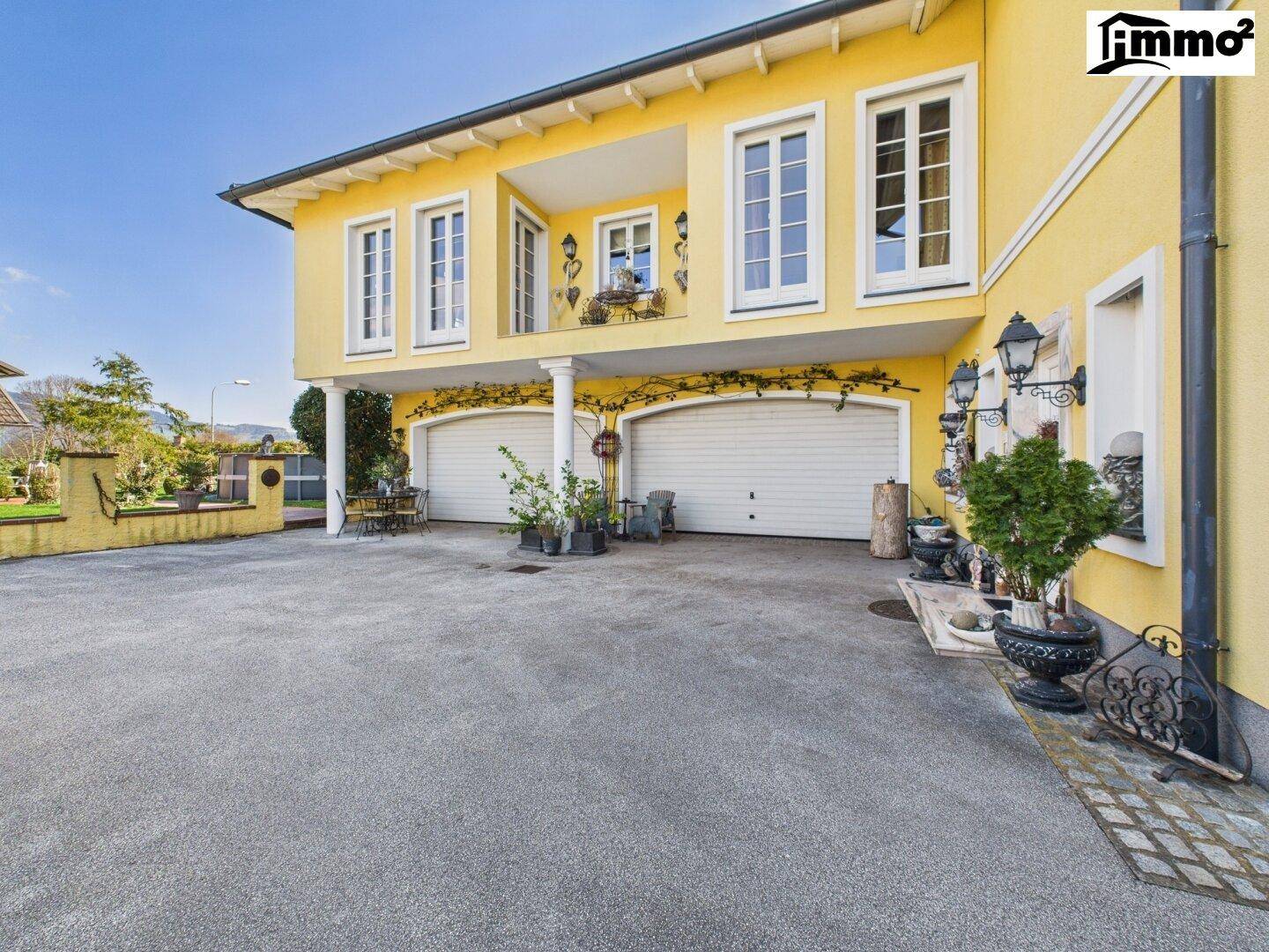 Seitenansicht des Hauses mit zwei Garagentoren, einem kleinen Balkon und dekorativen Elementen.