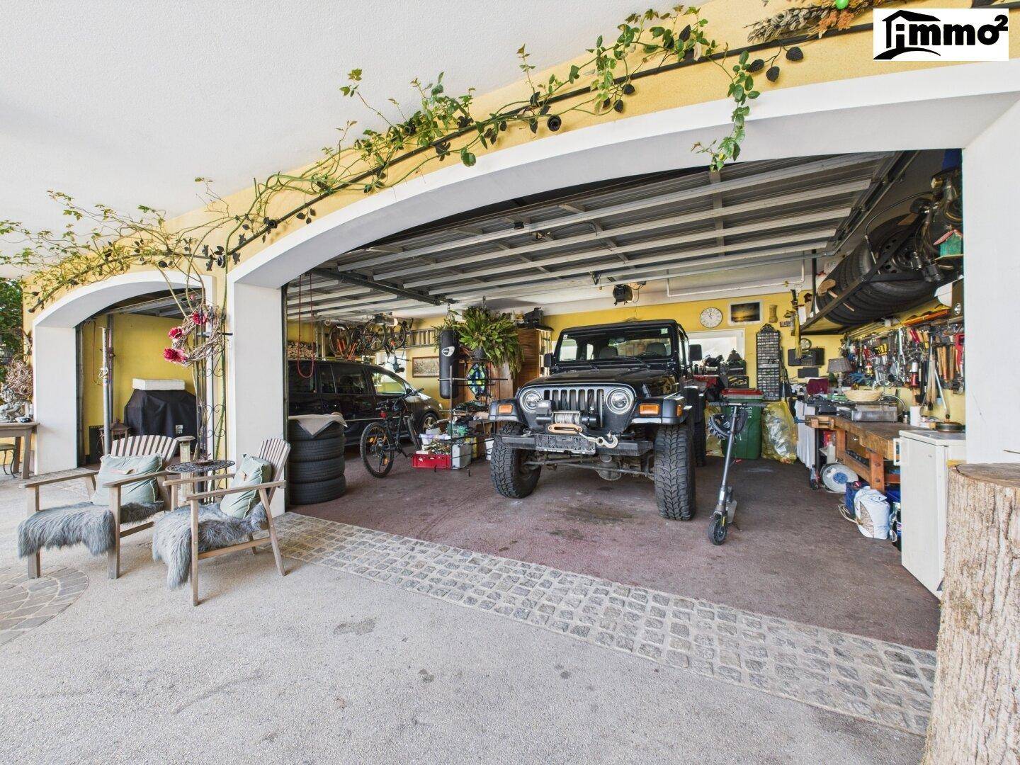 Geräumige Garage mit Werkstattbereich, Fahrzeugen und vielseitigem Stauraum.