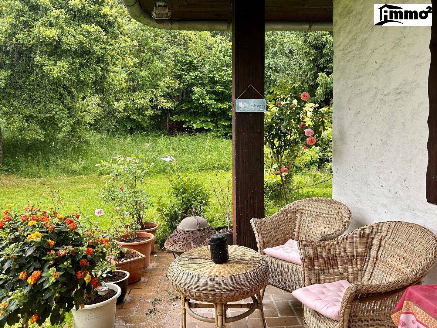 Gemütliche überdachte Terrasse mit Korbmöbeln und Blick ins Grüne.