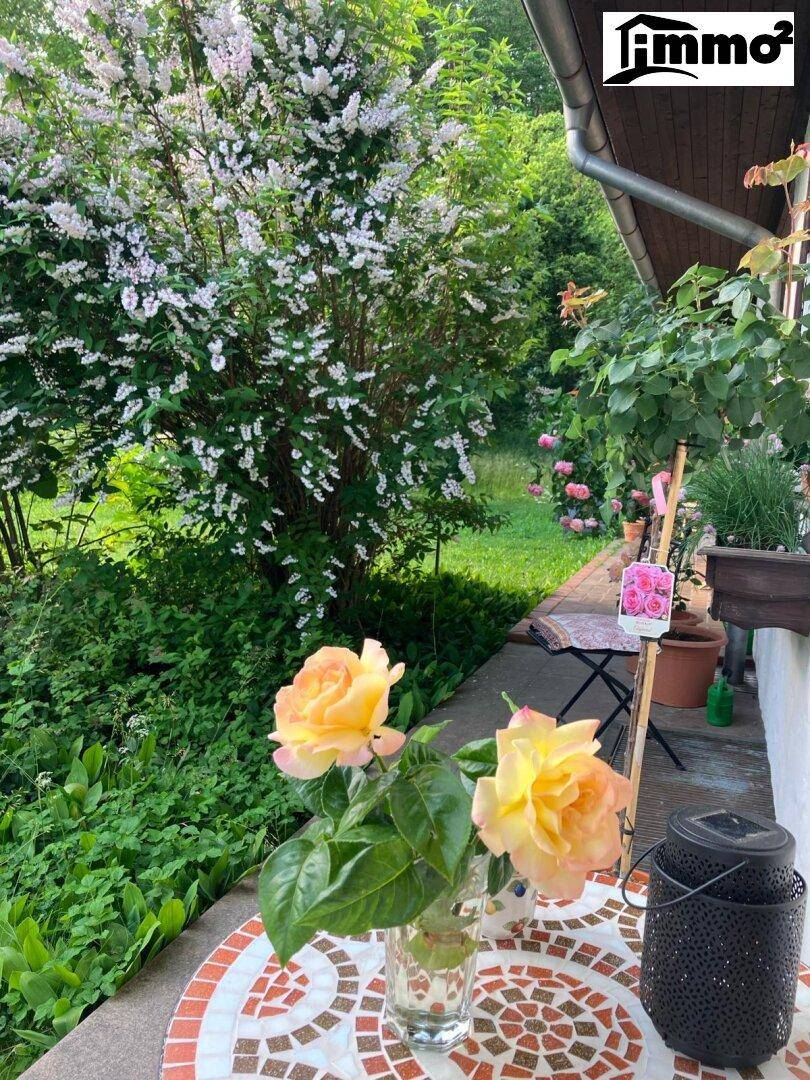 Detailaufnahme eines Mosaiktisches auf der Terrasse mit frischen Rosen und blühendem Garten.