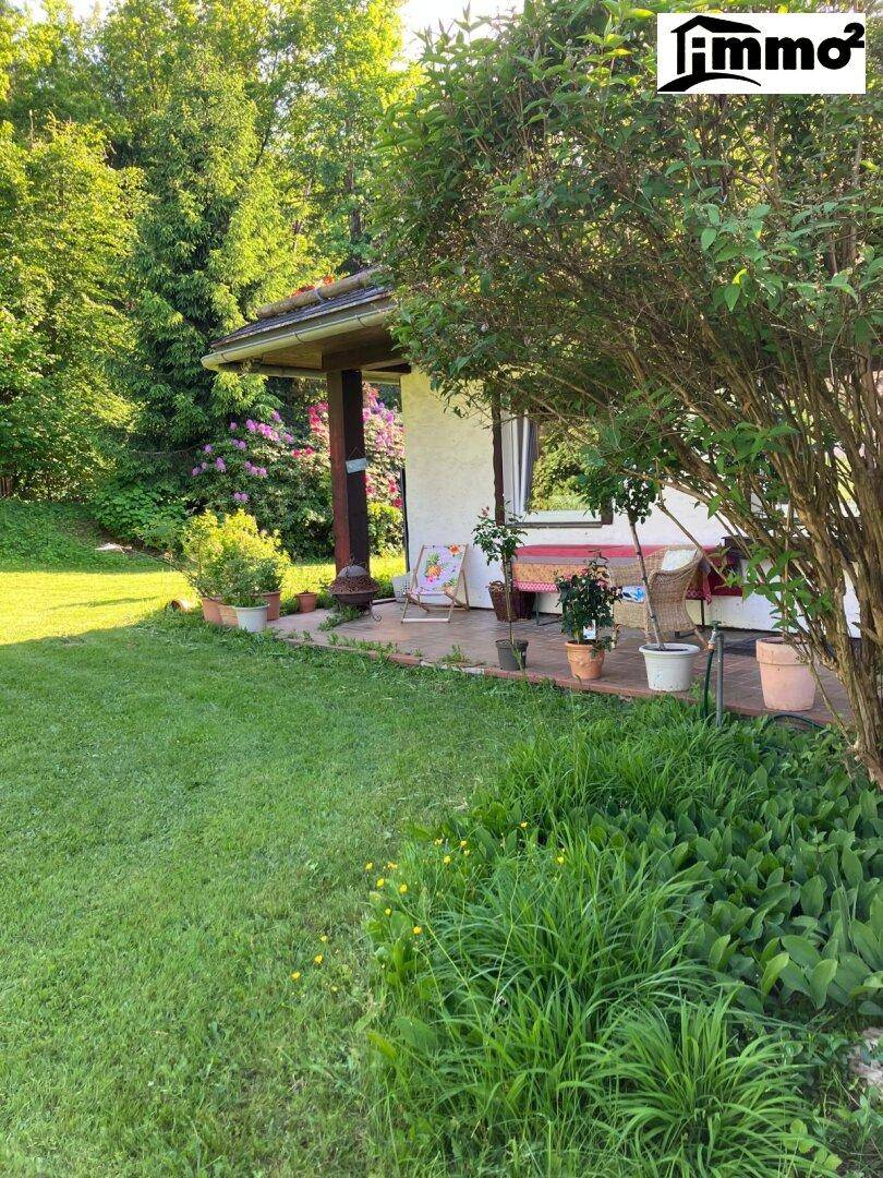 Überdachte Veranda mit Sitzgelegenheiten und Blick auf den weitläufigen, grünen Garten.