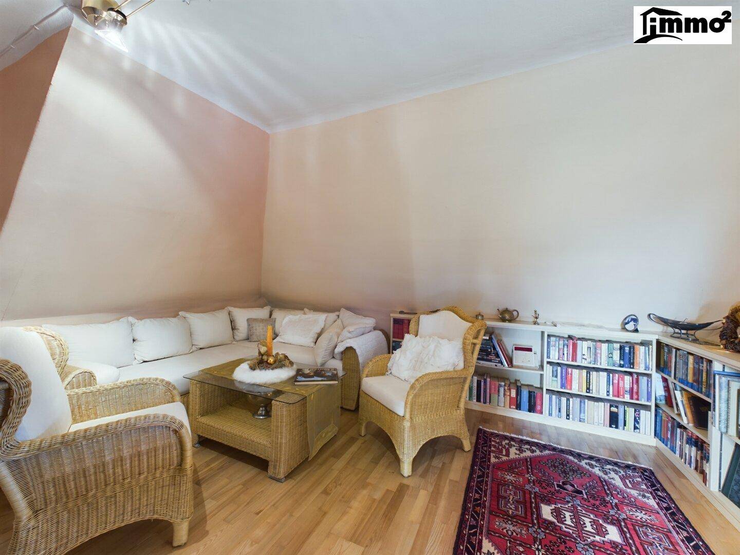 Helles Wohnzimmer mit bequemer Sitzecke, Bücherregalen und Holzboden.