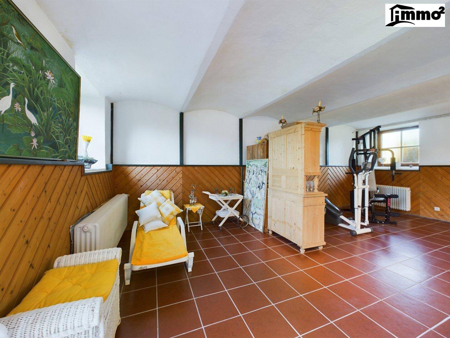 Vielseitiger Raum mit Fitnessgeräten, Holzvertäfelung und Fliesenboden.
