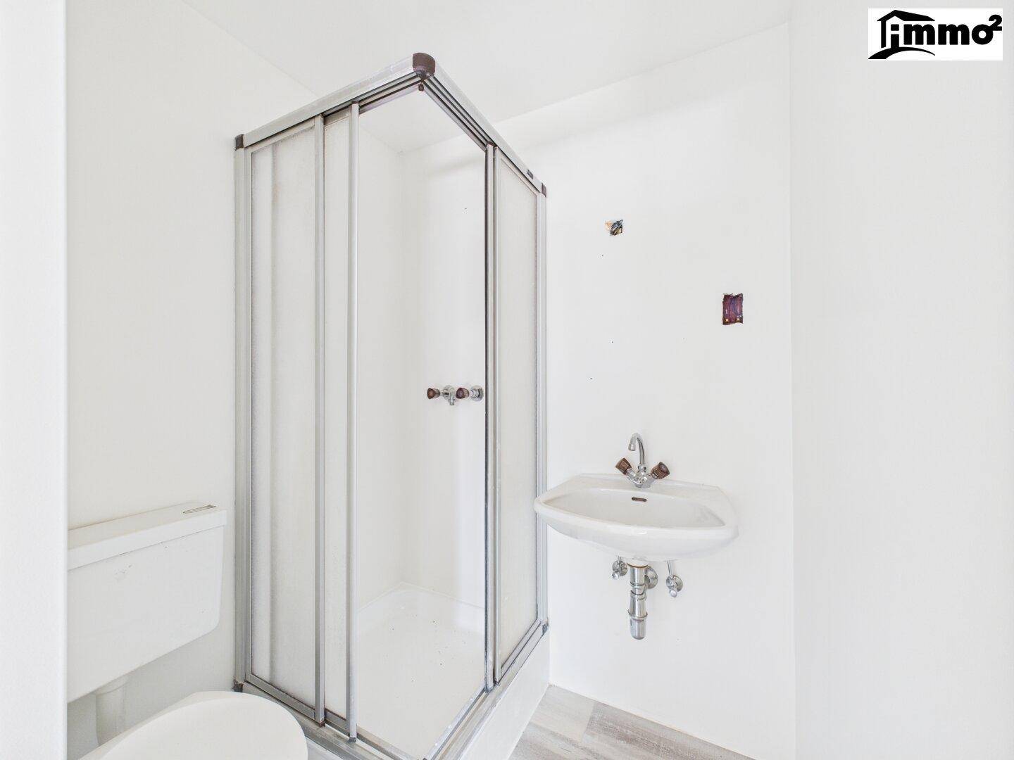 Badezimmer mit Duschkabine, WC und Waschbecken, in einfacher, funktionaler Ausstattung.