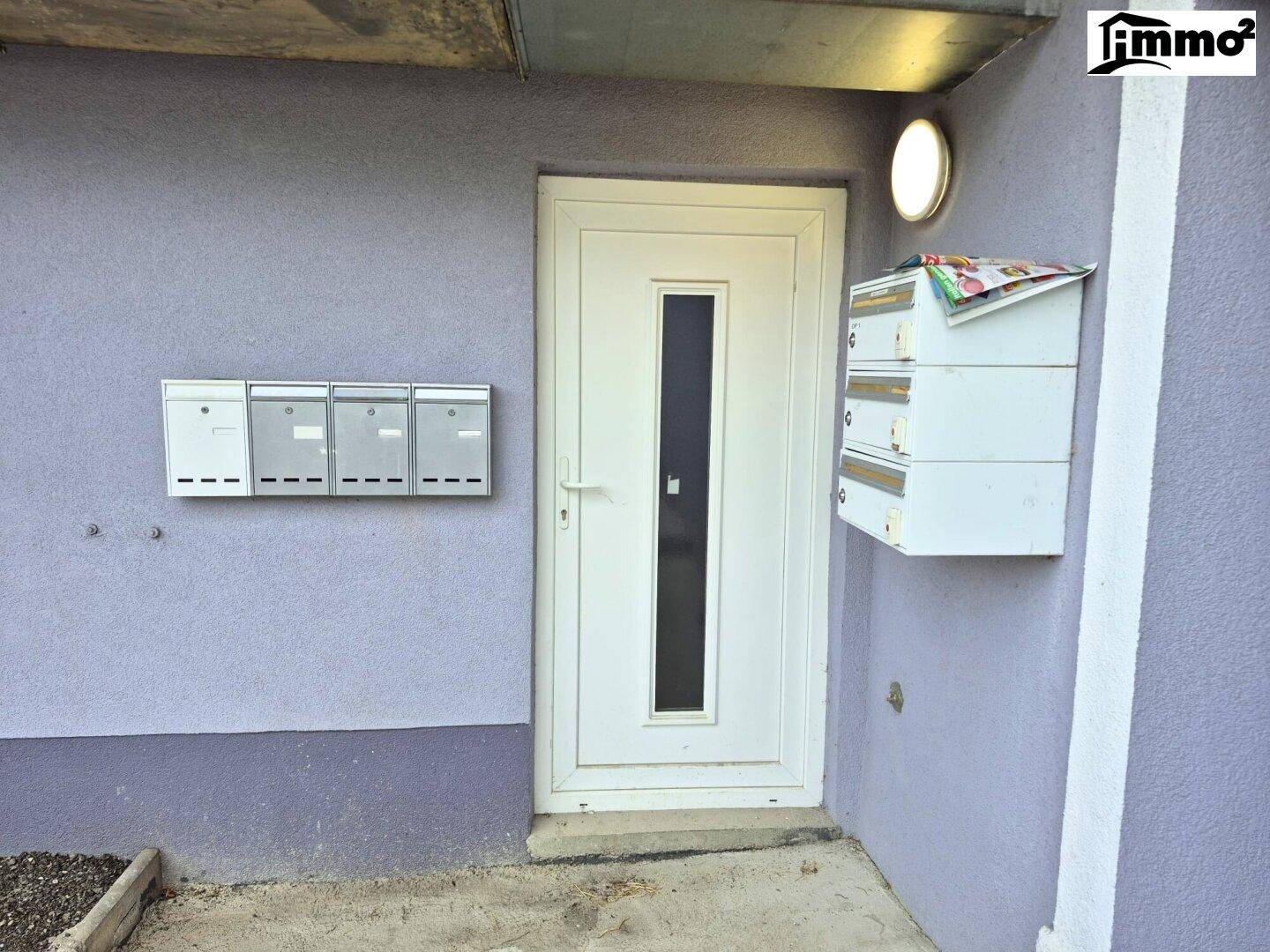 Eingangstür des Gebäudes mit mehreren Briefkästen an der Fassade.
