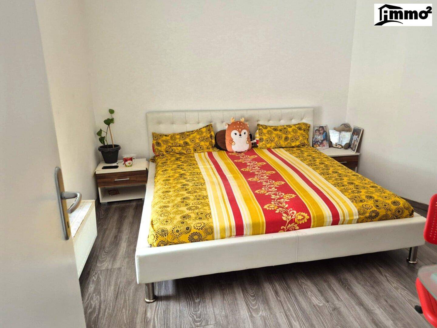 Schlafzimmer mit Doppelbett, Nachttischen und farbenfroher Bettwäsche.