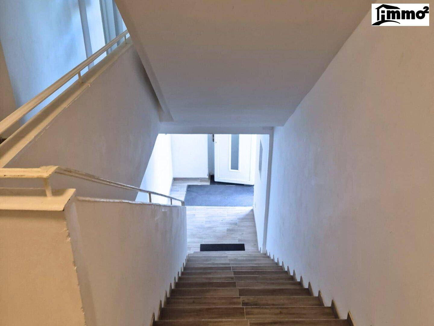 Innenbereich mit Treppenhaus und hellem Fliesenboden.