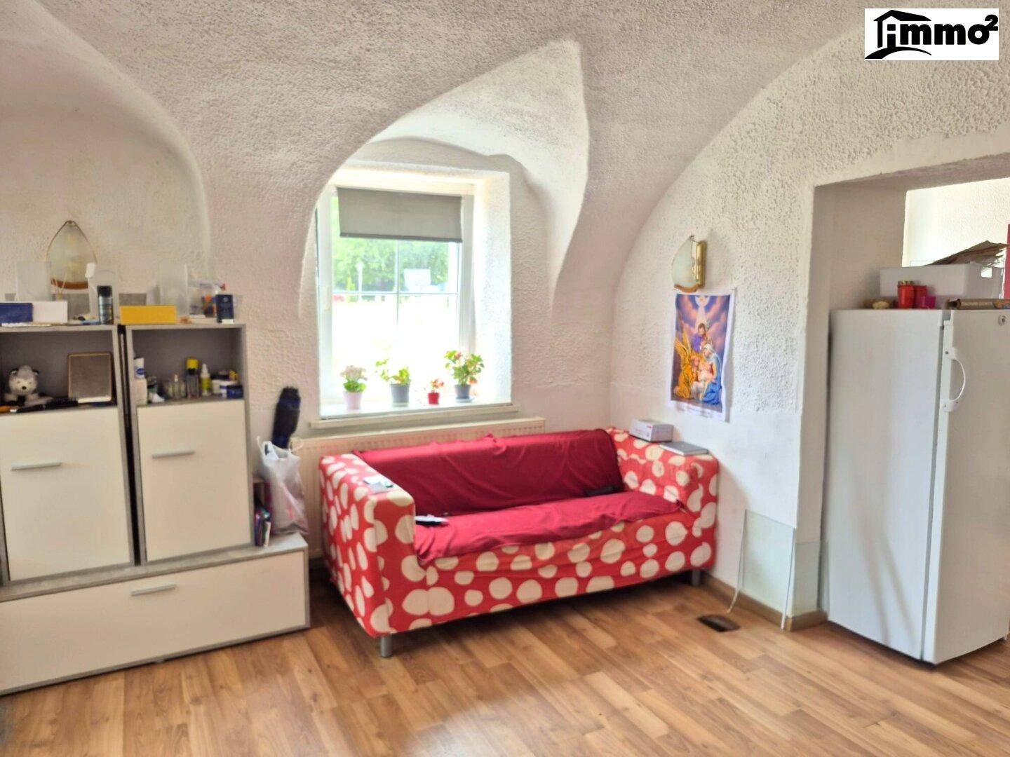 Raum mit einzigartiger gewölbter Decke, Fenster und rotem Sofa.