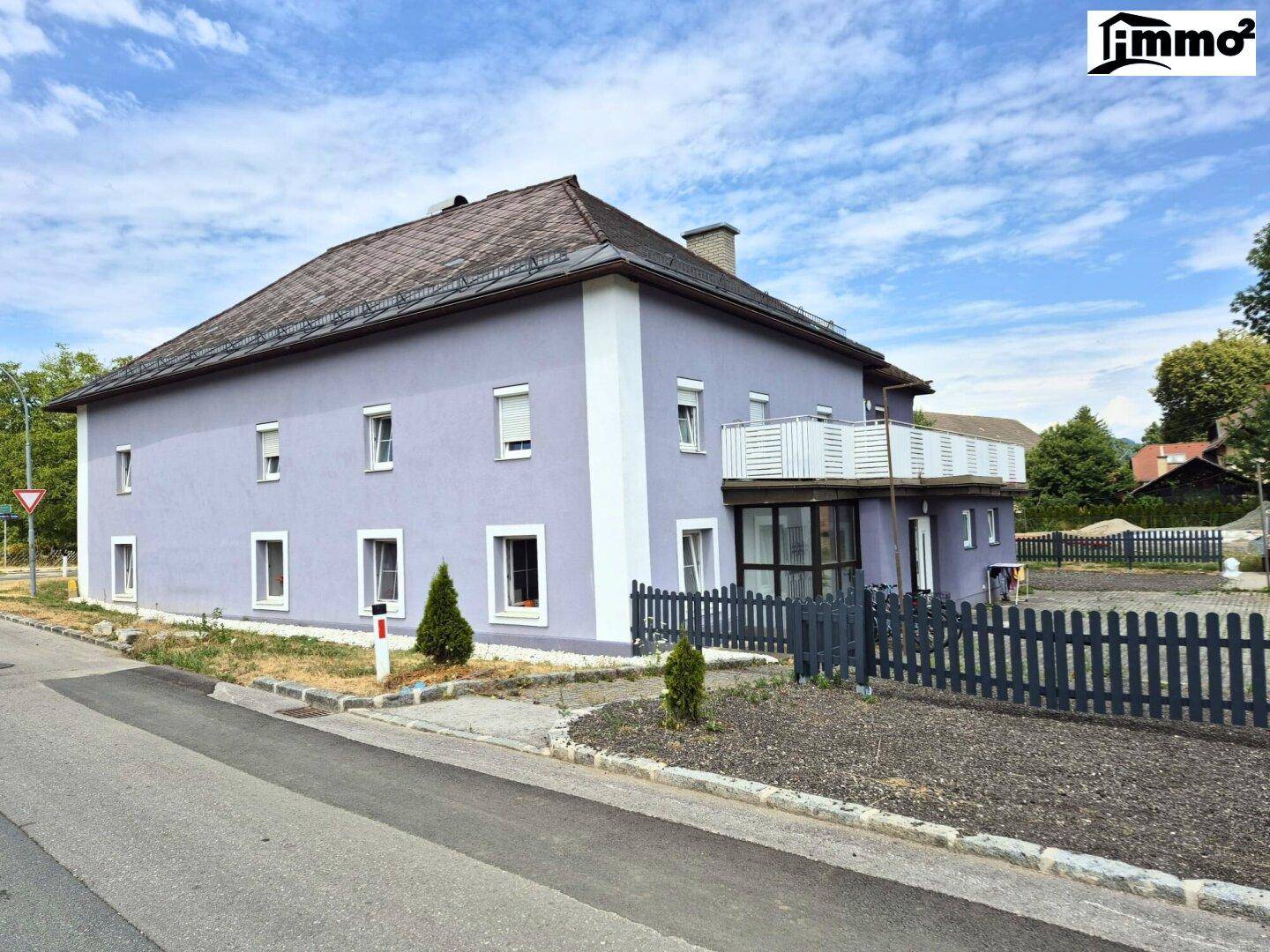 Seitenansicht des Gebäudes mit hellvioletter Fassade und traditionellem Dach.