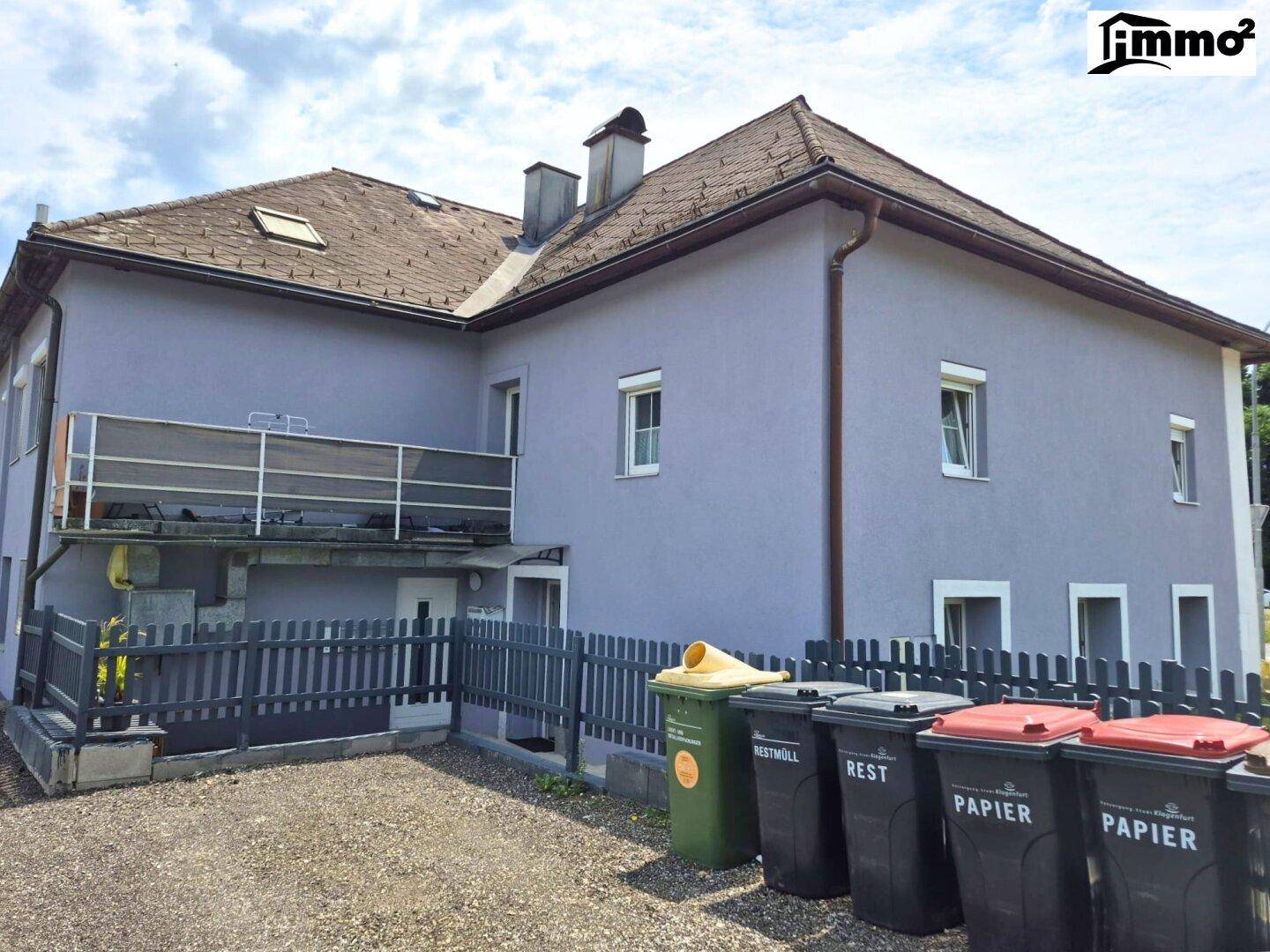 Rückansicht des Hauses mit Mülltonnen und einem kleinen Balkon.