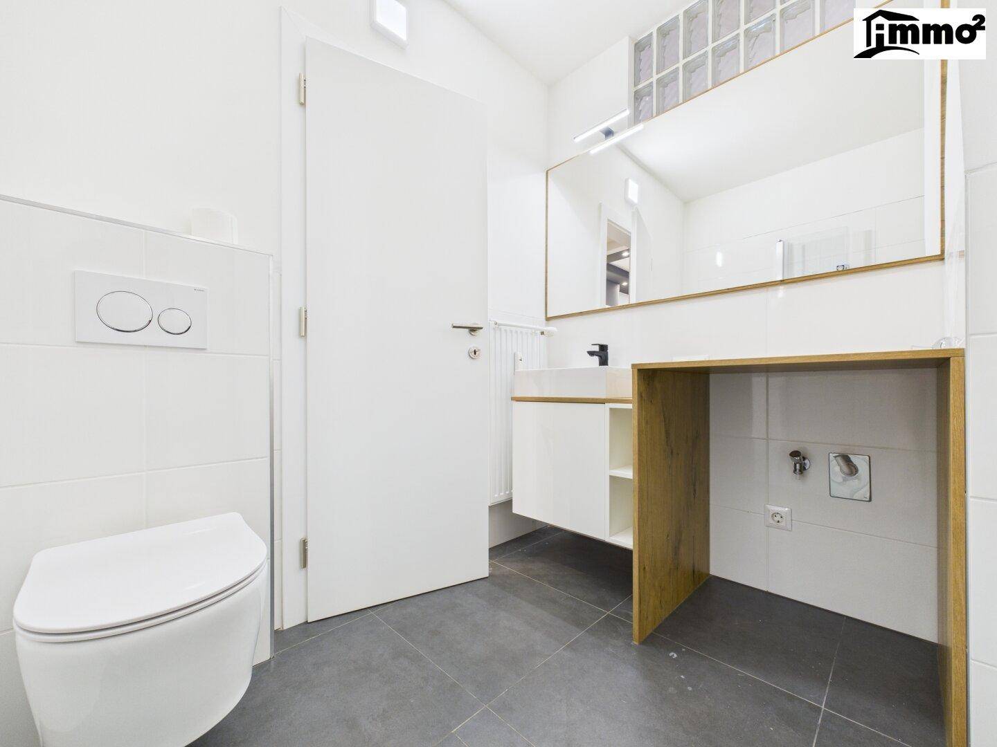 Modernes Badezimmer mit Wand-WC, Einzelwaschbecken und großem Spiegel.