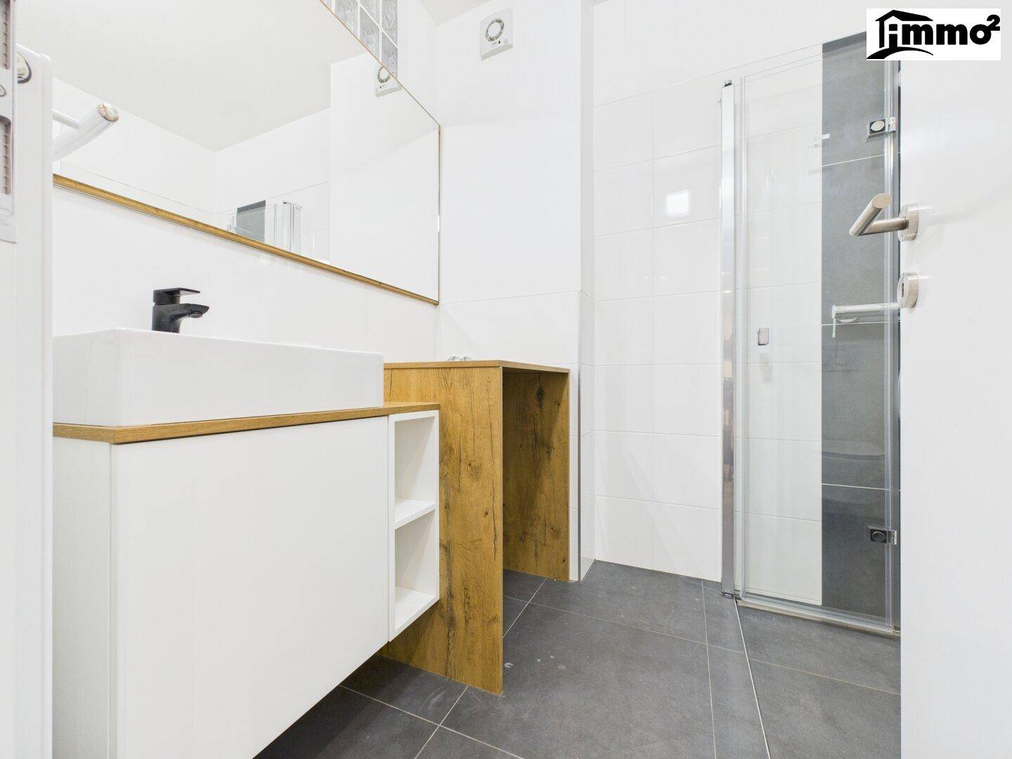 Modernes Badezimmer mit Duschkabine, Einzelwaschbecken und großem Spiegel.