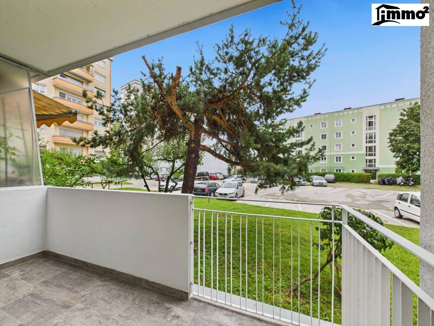 Geräumiger Balkon mit Blick auf Bäume, Parkplätze und umliegende Gebäude.