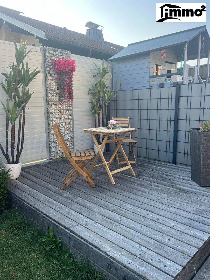 Gemütliche Holzterrasse mit Gartenmöbeln und dekorativem Sichtschutz im Garten.