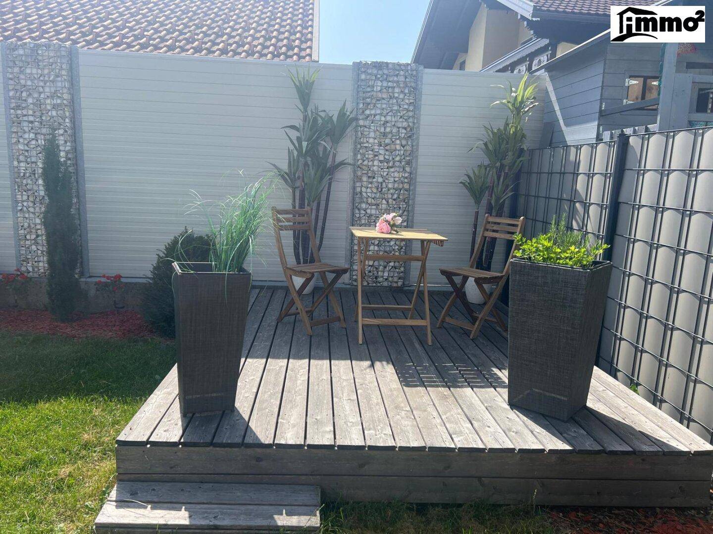 Holzterrasse im Garten mit Sitzgelegenheiten und dekorativen Pflanzenkübeln.