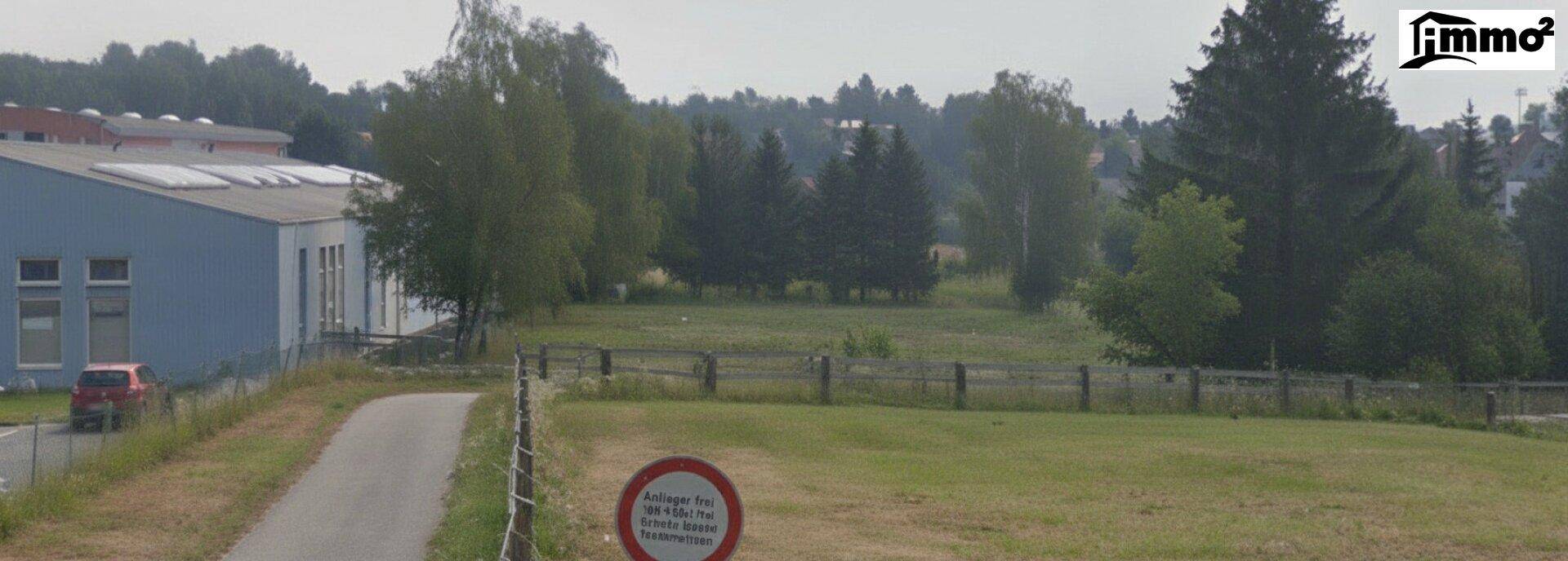 Panoramablick auf ein weites Feld mit einem blauen Gebäude, einer Straße und einem Verkehrsschild.