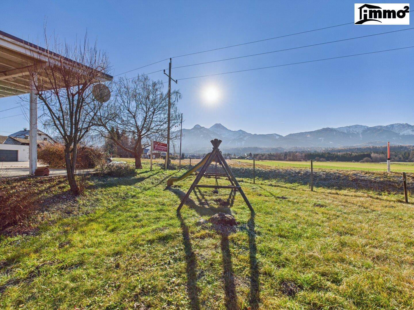 Grüner Gartenbereich mit einem hölzernen Spielgerät und malerischem Bergblick.