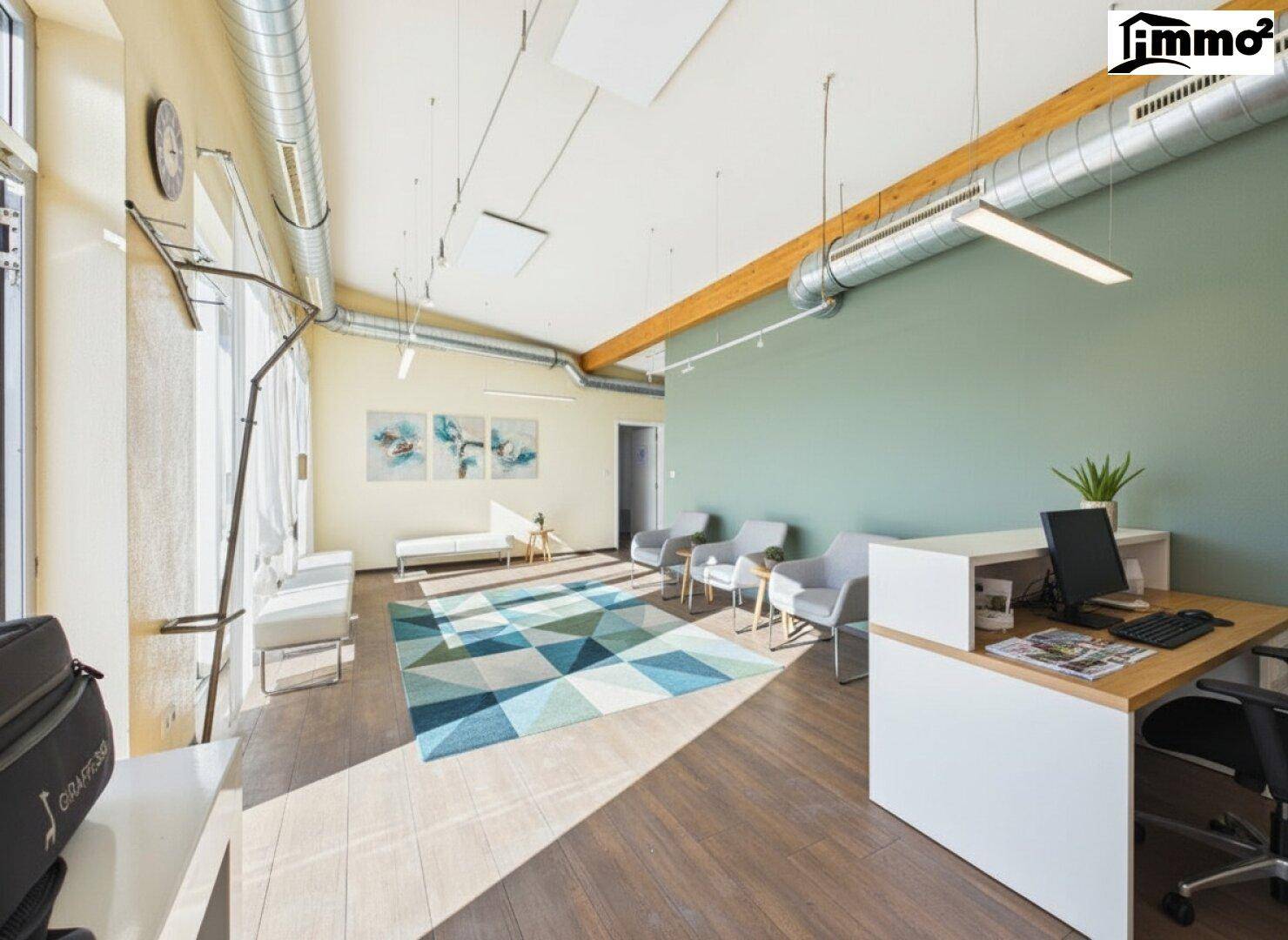 Heller Büro- und Wartebereich mit Schreibtisch, Stühlen, farbigem Teppich und einer grünen Akzentwand.