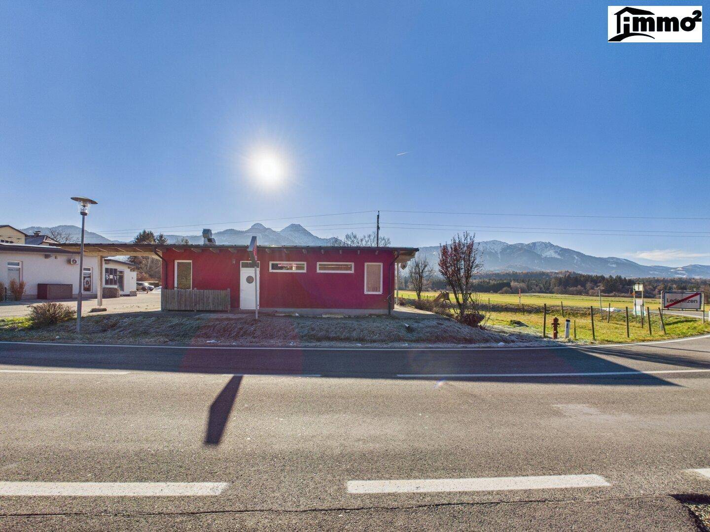 Rotes Gebäude an einer Straße gelegen, mit weitem Blick auf die umliegende Berglandschaft.
