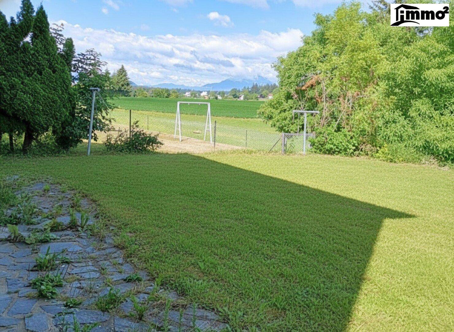 Großer Rasenbereich mit Schaukel und weitem Blick auf die umliegende Landschaft und Berge.
