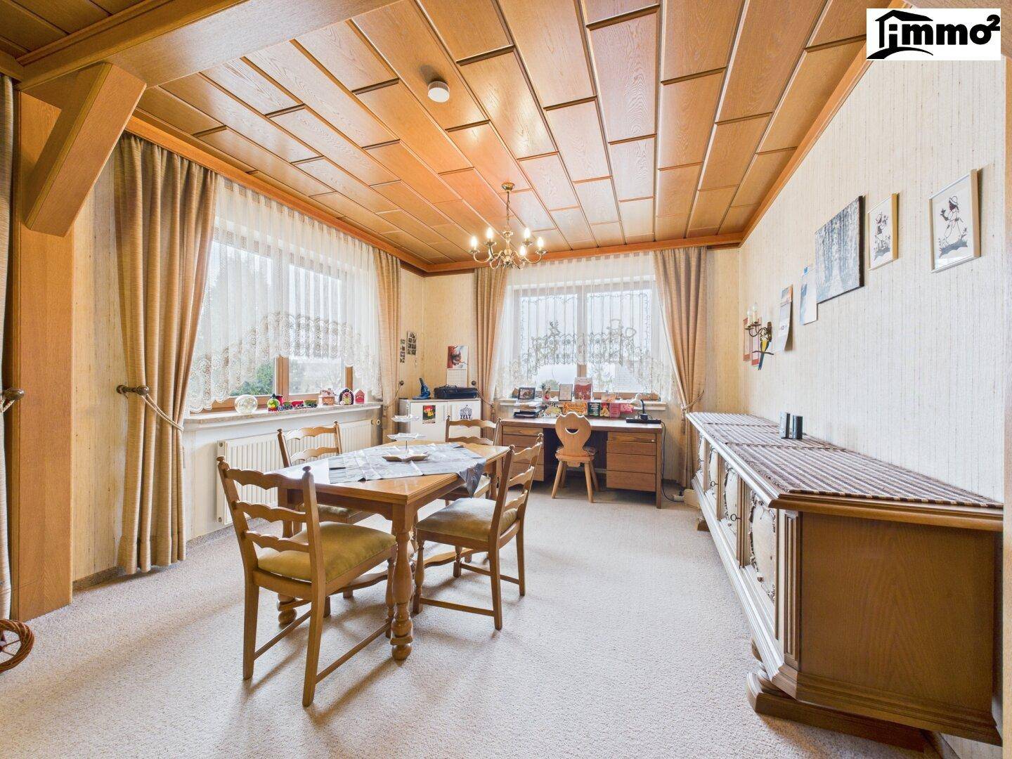 Essbereich mit Holztisch, Stühlen und einem Schreibtisch, ergänzt durch eine Holzdecke.