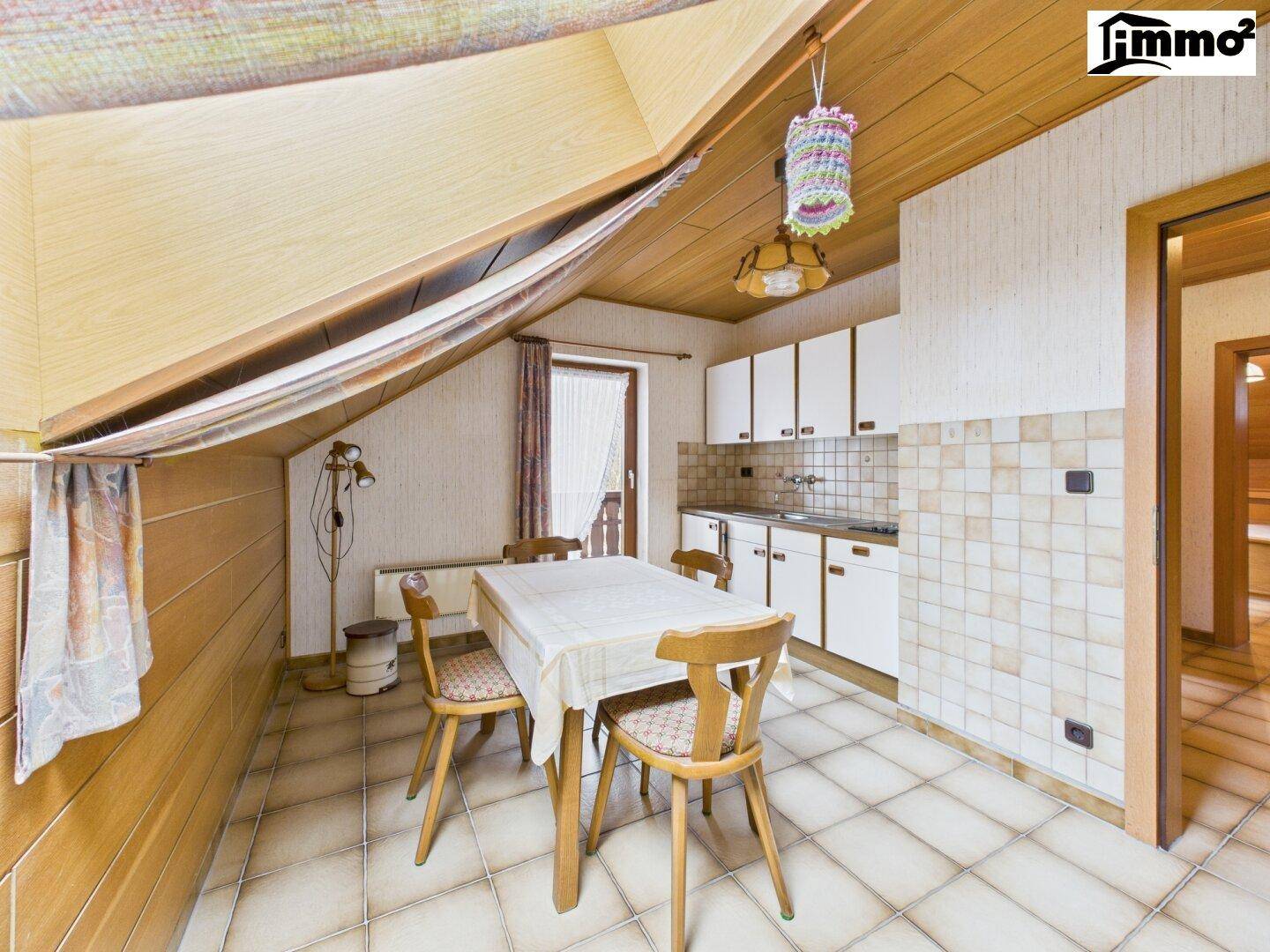 Kleine Küchenzeile im Dachgeschoss mit Essbereich und schrägen Wänden unter der Holzdecke.