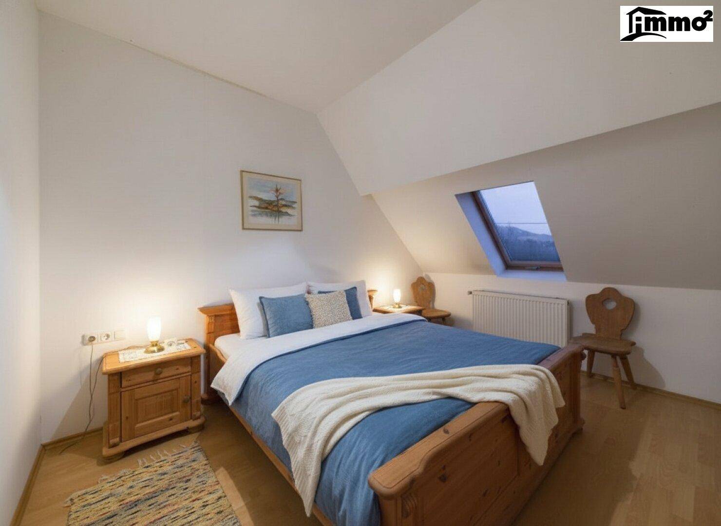 Gemütliches Schlafzimmer im Dachgeschoss mit Holzbett, Nachttischen und Dachfenster.